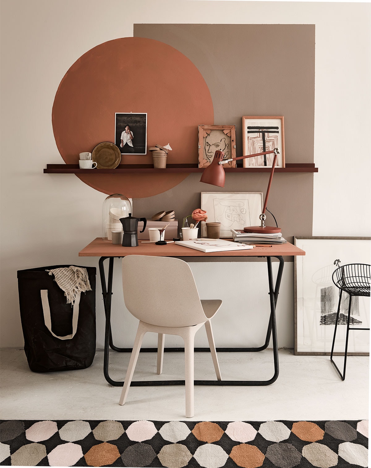Op de wand rechthoek in Somerset Mauve, cirkel in Kenyan Copper, matte krijtverf, wandplank in Cardinal Red, tafelblad in Kenyan Copper matte lak (Pure &amp; Original). Tafel (Combitex). Bureaulamp Arod, stoel Odger, kleed Torrild (Ikea). Papieren zak, bordje op wandplank, roze opbergdoos (Kwantum). In zak plaid Sigrid (Trendhopper). Wandplanken, glazen stolp, percolator, diverse kartonnen bekers, schildersdoek, klein glazen vaasje, mokken (Xenos). Draadstalen kruk (Loods 5). Kunst van SBK Kunstuitleen Amsterdam.