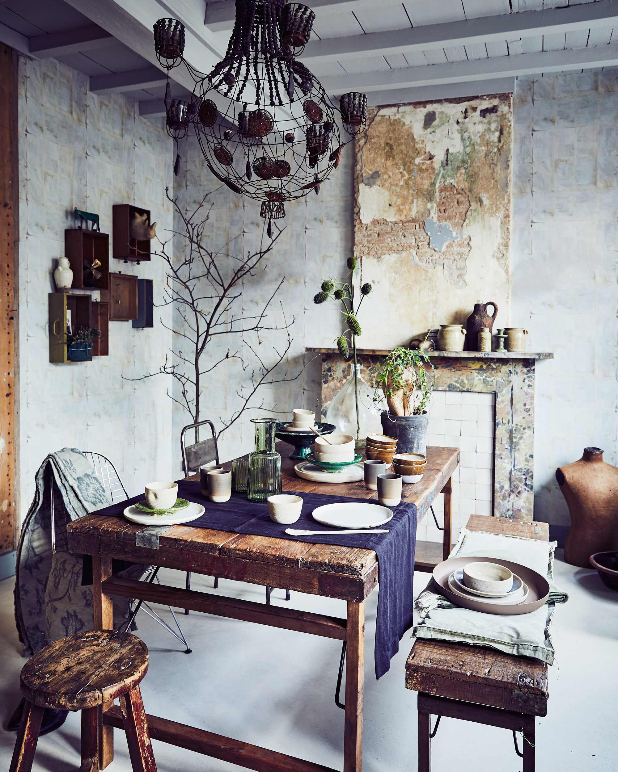 Lamp, linnen stof met blauwe bloemenprint per meter (Brecht Murré Atelier). Oude stalen stoel, houten kruk (Neef Louis). Stalen stoel, houten tafel, houten bank, zwarte tafelloper (Raw Materials). Grote bruine schaal, groene plaid op bank (vtwonen.nl). Groot bord/schaal Pebbles White, borden Cloud White, kom Basalt Grey, kommen Natural, kop Dimple Natural, mok Basalt Grey, bord Basalt Grey, lepels (Annemieke Boots Ceramics). Klein groen bordje, tak in vaas, schaal groen aardewerk, glazen kan, bruine schaaltjes, groene kandelaar (De Weldaad). Roomwitte mosterdpot van Linda’s Hoekje (Jan van IJken). Bruine houten fles (Van Dijk &amp; Ko). Overig privébezit.