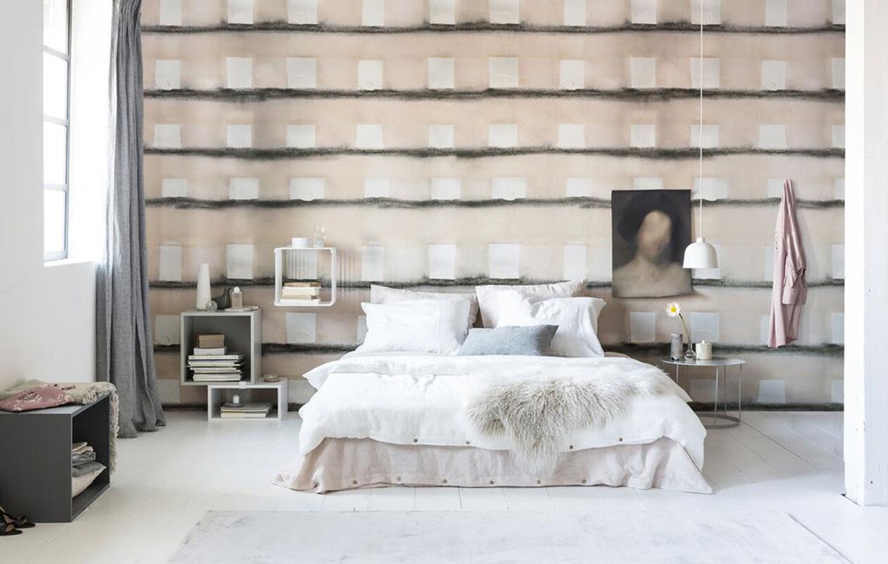 Op maat geprint behang Pulvis (Wall&amp;dèco). Vloerkleed Chrome Zinc (vloerkledenwinkel.nl). Linnen gordijn in kleur Charcoal, linnen dekbedovertrekin kleur Blush en Pure White, linnen kussenslopen in kleur Blush en Pure White, linnen kussen in kleur Charcoal, stapel linnengoed in donkergrijze kast (By Mölle). Donkergrijs vak, lichtgrijs vak, wit vak van demodulekast Stacked van Muuto, witte hangende kubus van staaldraad van Montana, witte hanglamp van Muuto (Coos de Wit Wonen). Roze toilettas, witte tadelaktpot met deksel, roze jurk (MaisonNL). Grijze deken met kreukeleffect (Hay Amsterdam). Witte karaf, lichtroze schapenvacht (Bolia). Porseleinen vogel (&amp;klevering). Bodywash van Byredo (Skins Cosmetics). Glazen bolvaasje (Fleurmonde). Roze canvas notitieboek metleren vetersluiting, witte keramieken schaal met zachtroze onderkant van Annemieke Boots (Restored). Glas (HK Living). Poster met print (Gurilla Artstudio). Ronde metalen tafel in kleur zijdegrijs (’K Willem in Huis). Overig privébezit. vtwonen 04-2018 | Fotografie Sjoerd Eickmans | Styling Danielle Verheul
