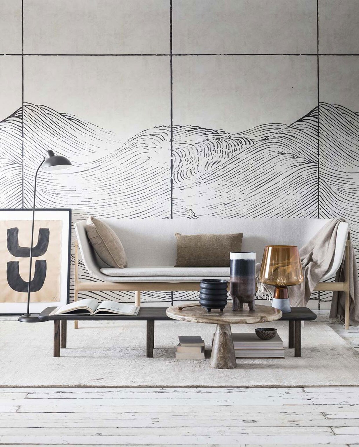 Op maat geprint behang behang Waves van Coordonné (Van Sand). Vloerkleed Blade Putty (vloerkledenwinkel.nl). Kunstwerk in lijst van Anne Older Kalter (Six and Sons). Zwarte vloerlamp van Republic of Fritz Hansen, merinowollen plaid van Republic of Fritz Hansen, bruine glazen tafellamp met betonnen onderstel van (vtwonen). Bank Tailor Sofa met eikenhouten onderstel met lichtgrijze wolmix bekleding (Menu). Eikenhouten bijzettafel Piled geolied in kleur charcoal (Loof). Ronde bijzettafel Melting Pot Table Side gemaakt van gebruikt plastic (The Frozen Fountain). Houten lepel, zwarte vaas op pootjes (HK Living). Gestreepte vaas (Loods 5 Design). Velours kussen in beige, grof linnen kussen (Loods 5). Overig privébezit. vtwonen 04-2018 | Fotografie Sjoerd Eickmans | Styling Danielle Verheul