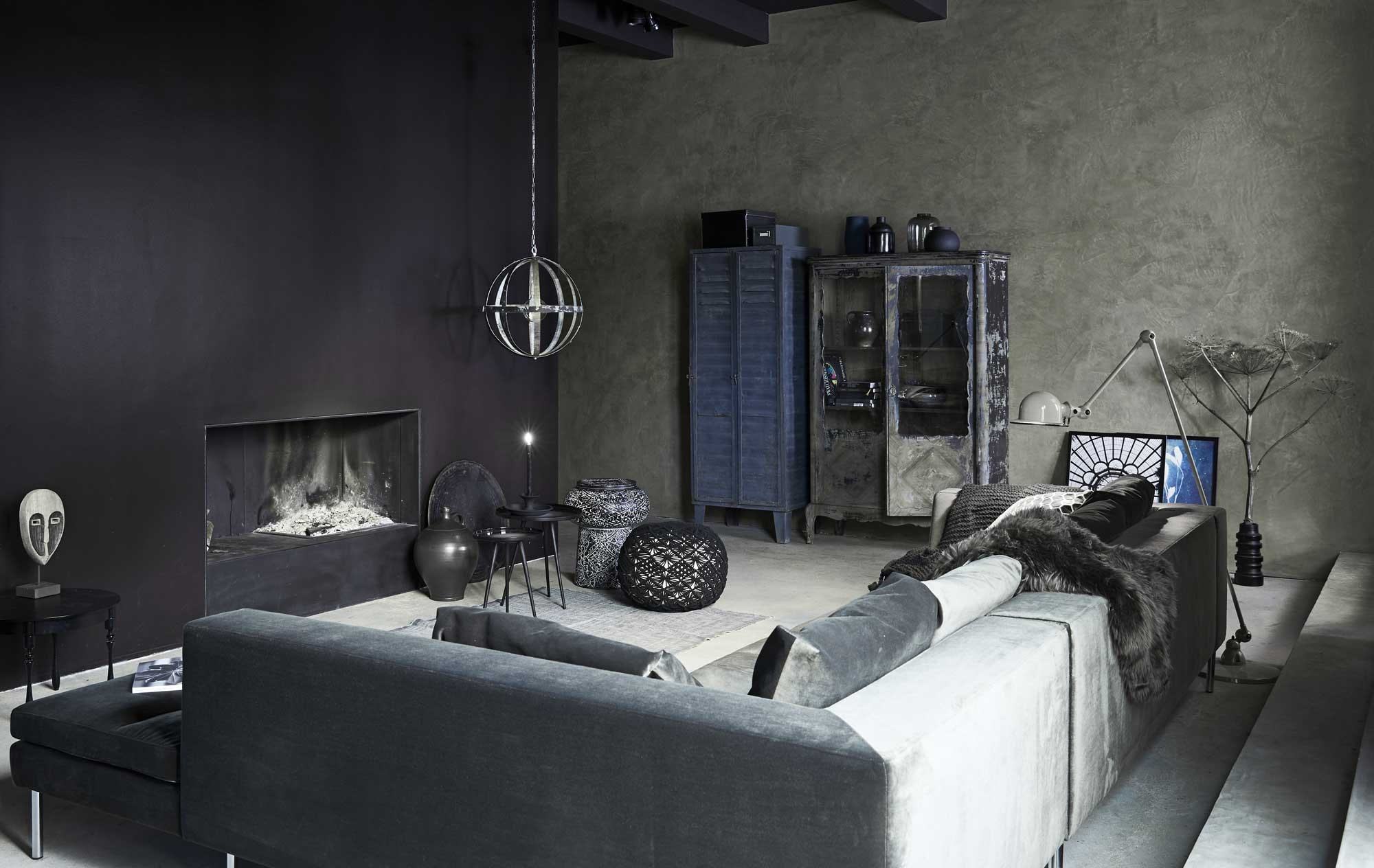 Hoekbank Timeless, twee elementen in stof Juke kleur Hunter, glazen vaas rechts op kast, gehaakte poef (Loods 5). Metalen locker, zwarte houten kast, metalen archiefkastje op locker, rond zwart metalen dienblad tegen de muur, gedroogde berenklauw (Spoor 38). Zwarte bolle vaas en diepblauwe vaas op de kast, plaid (House Doctor). Zwarte vaas, tweede van links op kast, vaas met tak op vloer, ornament met gezicht (HKliving). Kruik in kast, kruik op vloer (Van Dijk &amp; Ko). Driepoot tafeltjes (Zuiver). Kandelaar (vtwonen.nl). Gedecoreerde metalen bijzettafel/kruk, kussen met dessin, schapenvacht (Dutchbone). Zwart rond stalen tafeltje tegen de muur (Brecht Murré Atelier). Vloerkleed (vtwonen.nl). Posters van dakkoepel en tak in blauw (The Poster Club). Lijsten (IKEA).