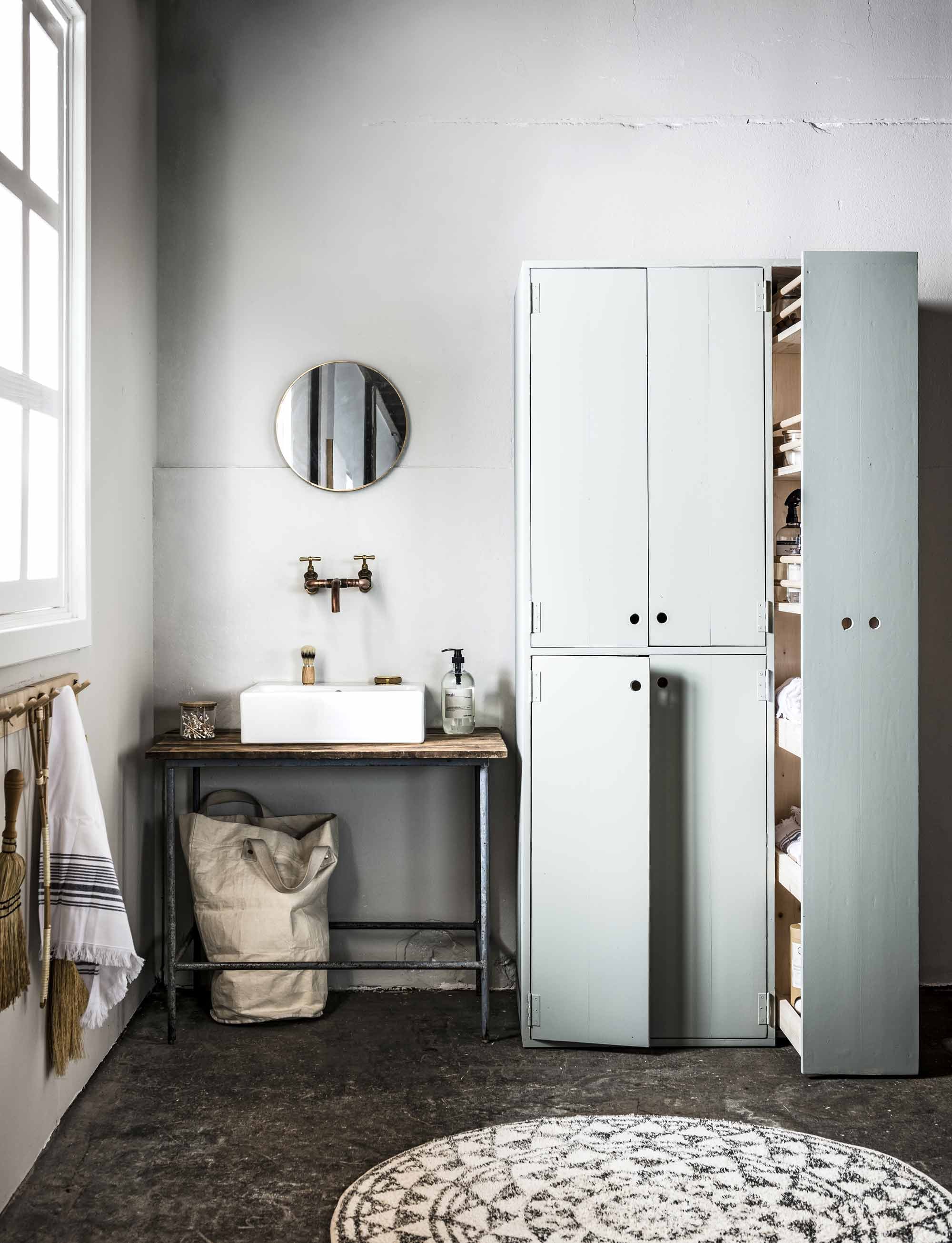 Kleur op de wand French Grey – Mid 162 (). Op maat gemaakte apothekerskast met ruimte voor wasmachine en droger, in de kleur Pigeon 25 (Farrow &amp; Ball) (). Aan de muur berkenhouten rekje, handstoffer, Japanse bezem, rotan mattenklopper hartvormig . Houten tafel met metalen onderstel (). Badmat (). Wastafel Yddingen (). Koperen kraan (). Ronde spiegel (). Armband van Return to Sender (). Glazen potje met houten deksel, scheerkwast, handdoek (). Houten wattenstaafjes ().  van Meraki () Wasmand privébezit.