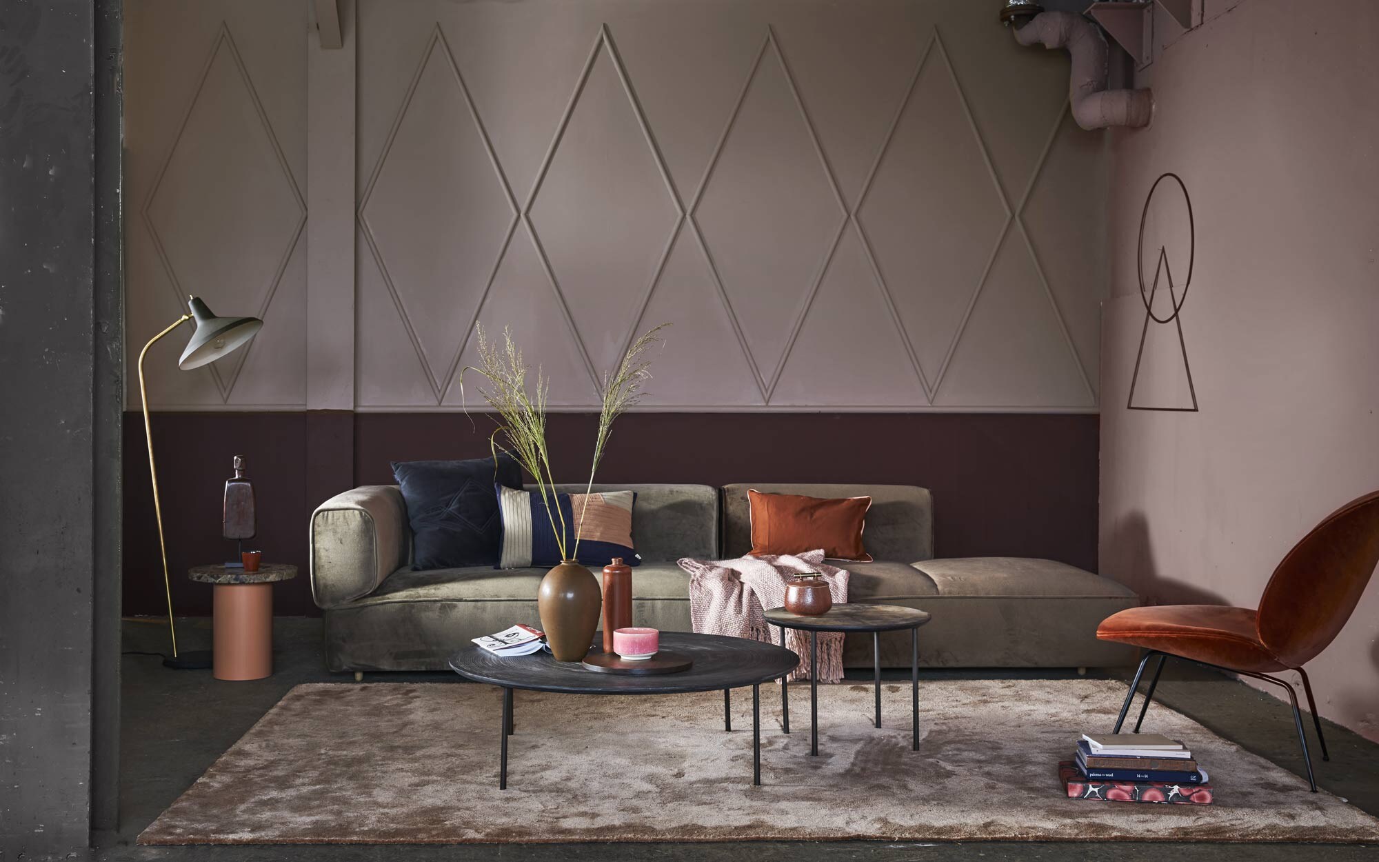 Muurverf achterwand Heart Wood extra mat van Flexa Pure, muurverf onder lambrisering Georgetown 309 flat emulsion van Paint &amp; Paper Library, muurverf rechter wand Hellebore 275 absolute matt emulsion van Little Greene (). Wanddecoratie Still Frame, cirkel, driehoek (). Fluwelen bank Poff van WON, 300x92x69 cm (lxbxh), donkergrijs kussen van Louise Roe Copenhagen, 60×60 cm, staande lamp G-10 van Gubi, fluwelen stoel Beetle lounge chair van Gubi (). Vloerkleed Frankly Amsterdam Move Slow, 200×300 cm, bijzettafel Enoki table met marmeren blad, 40×40 cm (Øxh) (). Kussen Angle Knit in donkerblauw, roze en wit (). Rechthoekig kussen Phulkari Rosewood ().  van Malagoon, rood kopje van Serax, pot met gouden handvat van House Doctor (). Beeld van man op bijzettafel, grote salontafel Multi Moon van Mos Design, 39×70 cm (hxØ), kleine salontafel (). Bruine bolvaas, langwerpige vaas van keramiek (). Roze geglazuurde kom van Studio Arhoj (). Boeken privébezit.