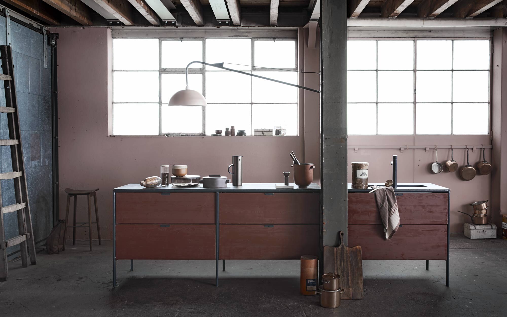 Roze muurverf Hellebore 275 absolute matt emulsion van Little Greene (). Keukenblok op maat gemaakt, houten ladder ().  van Ferm Living, Ø 38 cm,  Wonen Landelijke Stijl by J-Line, rode gietijzeren pot van House Doctor,  EM77 van Stelton,  van Sambonet, Ø 24,5 cm (). Wandlamp van staal, lengte 150 cm, koperen pannen, vintage vaasjes in vensterbank (). Bordeauxrode theedoek Grain Jacquard van Ferm Living, essenhouten pepermolen Drupe van Ferm Living (). Goudkleurige pollepel (). Bruine opbergdoos (). Houten deegrollers (). Grijze schaal When Objects Work, van glas met notenhouten deksel, van terracotta met eikenhouten deksel (). Tas van My Paper Bag (). Barkruk van Norr11 (). Glazen weckpotten (). Broodtrommel, koperen haken, boek, glazen opbergpot en kalebas privébezit.