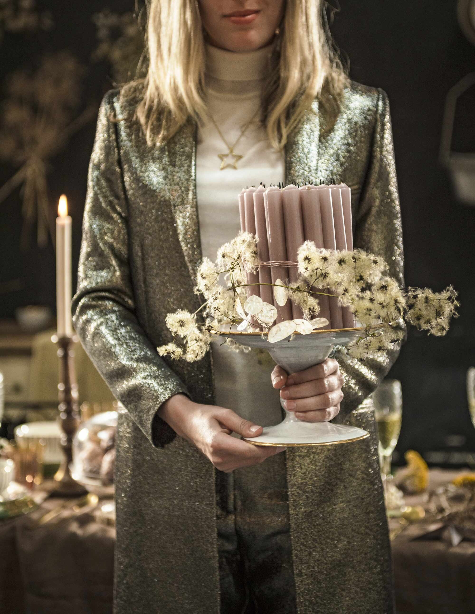 Witte schaal met gouden rand (Brecht Murré Atelier). Oud-roze kaarsen (Søstrene Grene). Gouden broek, gouden blazer, witte trui (Six and Sons). Gouden ketting (Anna+Nina). Krans gemaakt door Tuin van Judith.