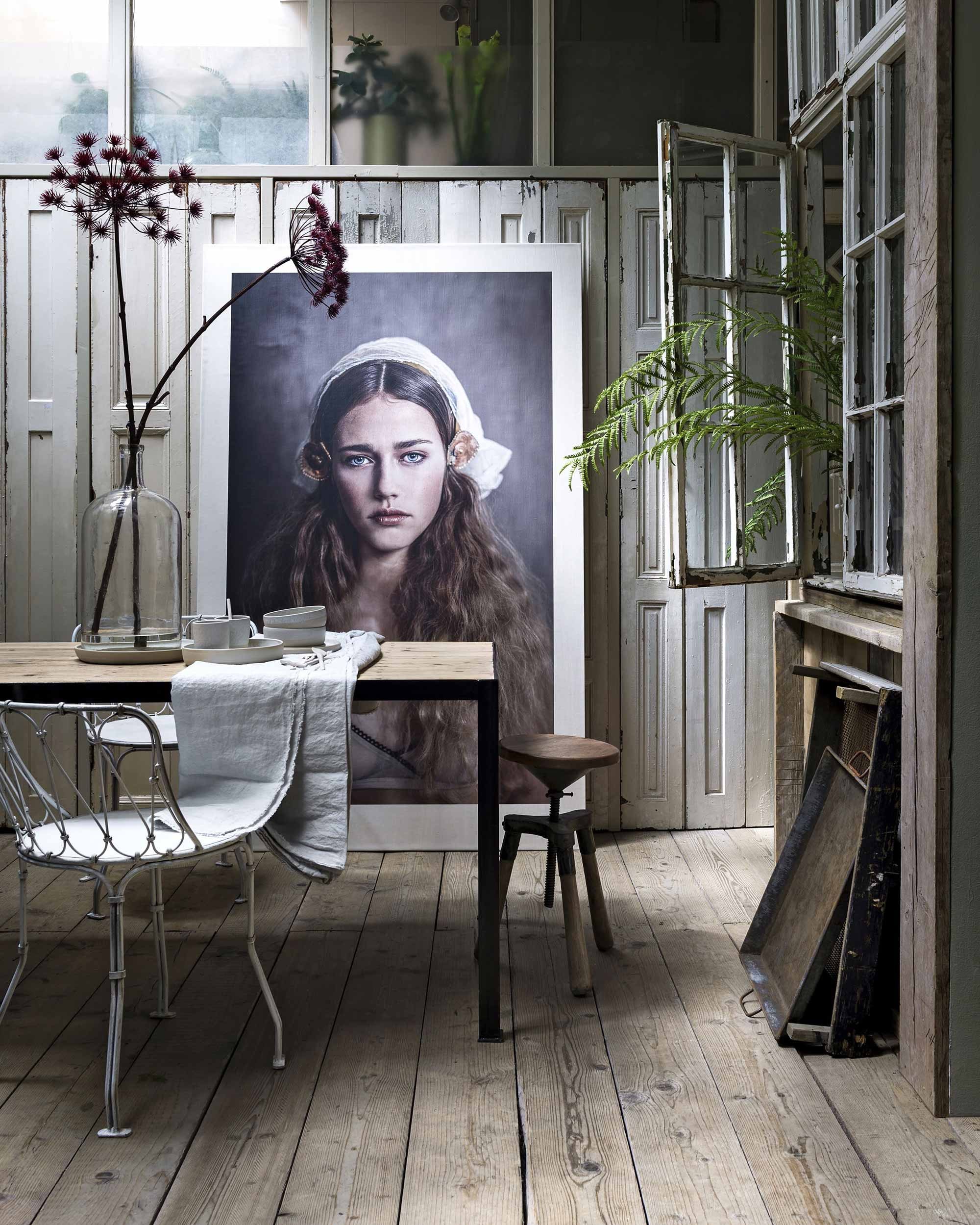 Tafel van hout en staal, kruk, witte stoel van staaldraad, dienbladen, oude vaas van glas, kunststof bloemen en plant (De Weldaad). Linnen tafelkleed (House in Style). Met de hand gedraaid keramiek serviesgoed van Annemieke Boots (Annemieke Boots Ceramics). Portret prijs op aanvraag (Rachel Dubbe).