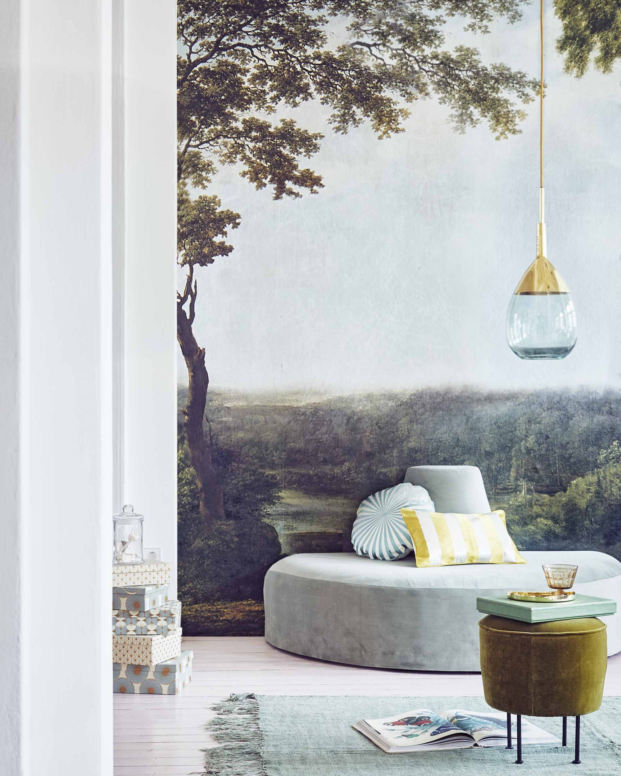 Behang Collaboration Tres Tintas M2600-1 van Rebel Walls (). Halfronde fluwelen bank Pouf with backrest van Tine K Home (). Zachtgroen linnen vloerkleed (). Kleine mosgroene poef van Gubi (). Dozen set van 6, kussen, geel gestreept kussen (). Glas op voet (). Gouden schaaltje (). Hanglamp van groen glas met goud van Ebb &amp; Flow ().