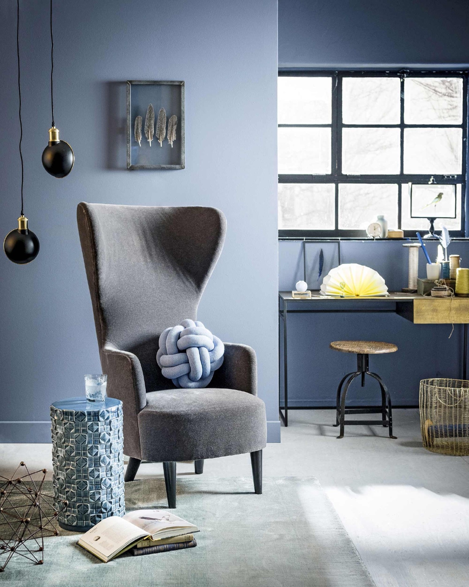 Juniper Ash 115, absolute matt emulsion (Little Greene). Velours Wingback Chair van Tom Dixon (Mobilia). Blauw kussen Knot van Design House Stockholm (misterdesign.nl). Vloerkleed Capsilo Teal (Designers Guild). Bijzettafel van blauw keramiek, gegraveerd bloesemblauw glas per 6, koperen bureau (Pols Potten). Gele waaiermap, geel bakje, goudkleurige schaar (Hay). Klossen, groot ijzermolecuul (Burbri Antiek). Draaikruk, zwart-gouden hanglampen per stuk (vtwonen). Ingelijste veren (Six and Sons). Draadmand (Sissy-Boy). Crèmekleurige beker set met bord en schaaltje (By Mölle). Zandloper (De Weldaad). Glazen doosje (MaisonNL). Groenwang parkiet in vitrine (Taxidermy). Kleine blauwe vaas, blauw vaasje, boeken (kringloop). Groene doos en klokje privébezit.