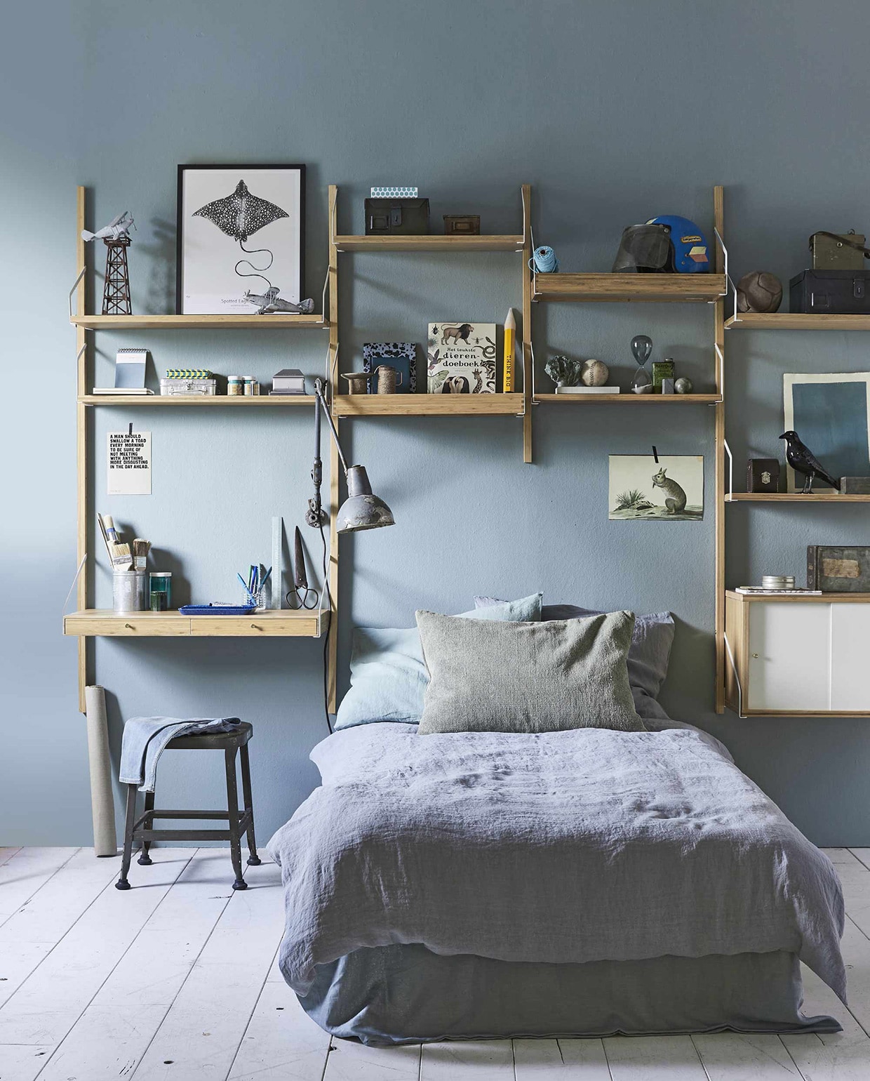 Kastenwand van wandkastensysteem Svalnäs, zoals hier afgebeeld (). Op de muur muurverf in kleur Oval Room Blue 85 van Farrow &amp; Ball (). In de kast: helm, leren bal, vintage vliegtuigen, oude miniatuur spoorwegonderdelen, kruk Lyon Barstools, bureaulamp (). Dierenboek, XL potlood, zwarte kraai (). Metalen opbergdoos klein, groot van Home Industrials (). Aluminium kistje, lage blauwe pennenbak, lichtblauwe liniaal, spelletjesdoos, lichtblauwe notitieboekjes (). Zilverkleurige perforator, zandloper, blauwe pennen (). Gevlekt schrift van Els &amp; Nel, afbeelding vis Spotted Eagle Ray (). Op bed: groen kussen (). Blauw linnen dekbedovertrek Blue Grey, kussensloop (). Overig privébezit., vtwonen 10-2017 | Fotografie Jeroen van der Spek | Styling Cleo Scheulderman