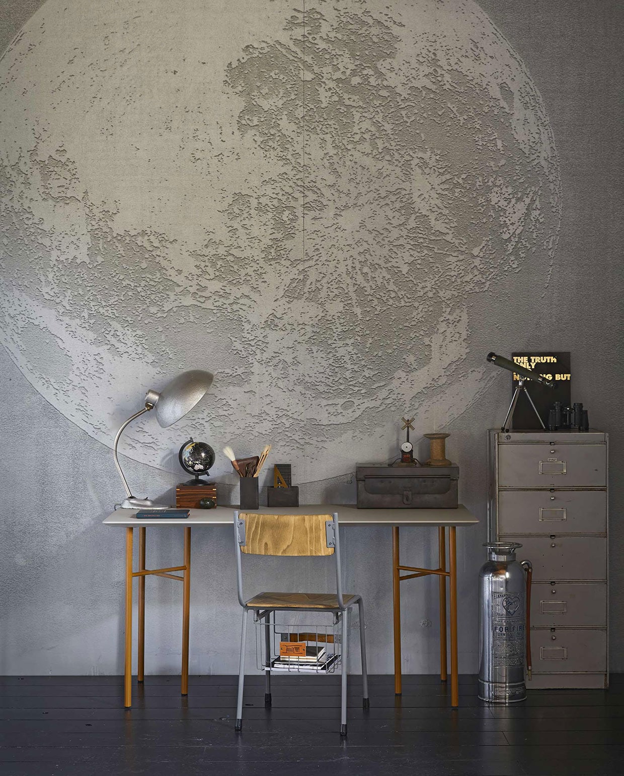 Behang Luna Plena WDLU1702 (). Gereedschapskist, brandblusser, bureaulamp, pennenbak hoog, pennenbak laag, kleppenkast (). Storage stoel (). Vintage sterrenkijker (). Tafelblad Mingle, okergeel tafelonderstel Mingle van Ferm Living (). Zwarte map met gouden tekst (). Klosje, leren etui met schaar (). Gouden geodriehoek (). Houten doosje met sterrenkijker (). Wereldbol en verrekijker privébezit. vtwonen 10-2017 | Fotografie Jeroen van der Spek | Styling Cleo Scheulderman