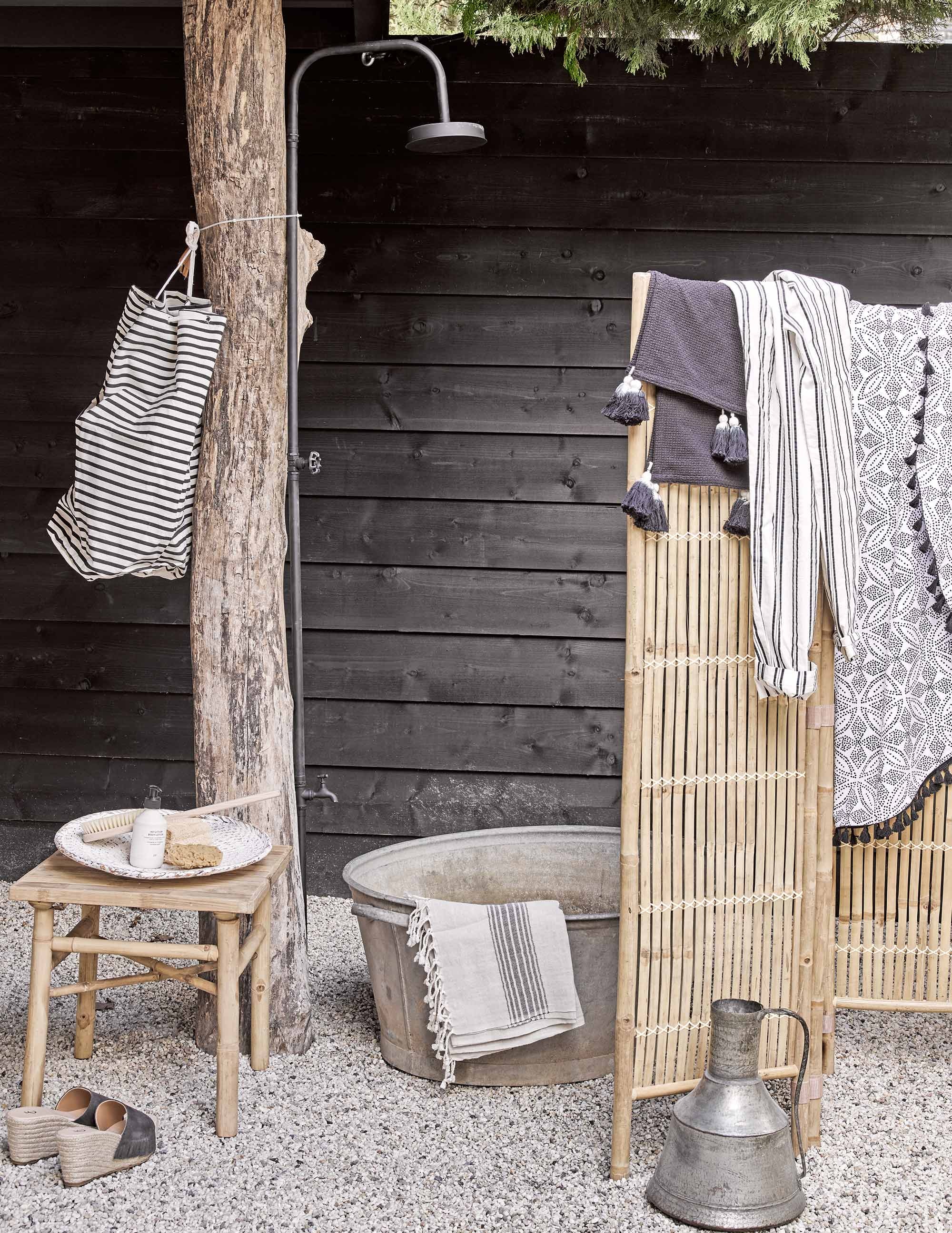 Buitendouche van Bloomingville, gestreepte plunjezak (). Zinken teil (). Slippers (). Gestreepte broek (). Zand-kleurige hamamdoek (). Witte schaal (). Ronde zwart-witte handdoek (). Zilveren kan (). Zwarte doek met kwastjes (). Overig privébezit.,