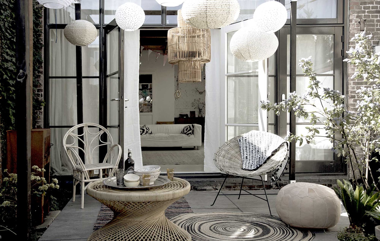 Pergola, Cubic Pergola Systeem (). Lampion large met zwart-witte stip, lampion medium met graniet/zwart/wit, lampion medium wit met gouden stip, lampion medium met roze-gouden stip (). Rotan lamp, rotan tafel, ronde potten, hoge potten (). Stoel links, houten schaaltjes, oranje glazen, keramische kommen in grijs-wit, poef (). ,  (HK Living). Dienblad in zilver (). Rotan stoel rechts(). over stoel (H&amp;M).  (Storebror). Tegels Solostone Beachwood Antracite van vtwonen (). Overig privébezit. vtwonen 08-2016 | Fotografie Sanne Tulp | Styling Anke Helmich