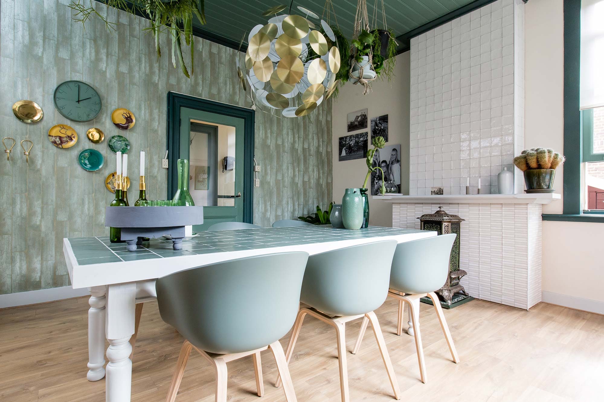 woonkamer met lichtgroene wand en grijze bank met witte stoelen en bijzettafel