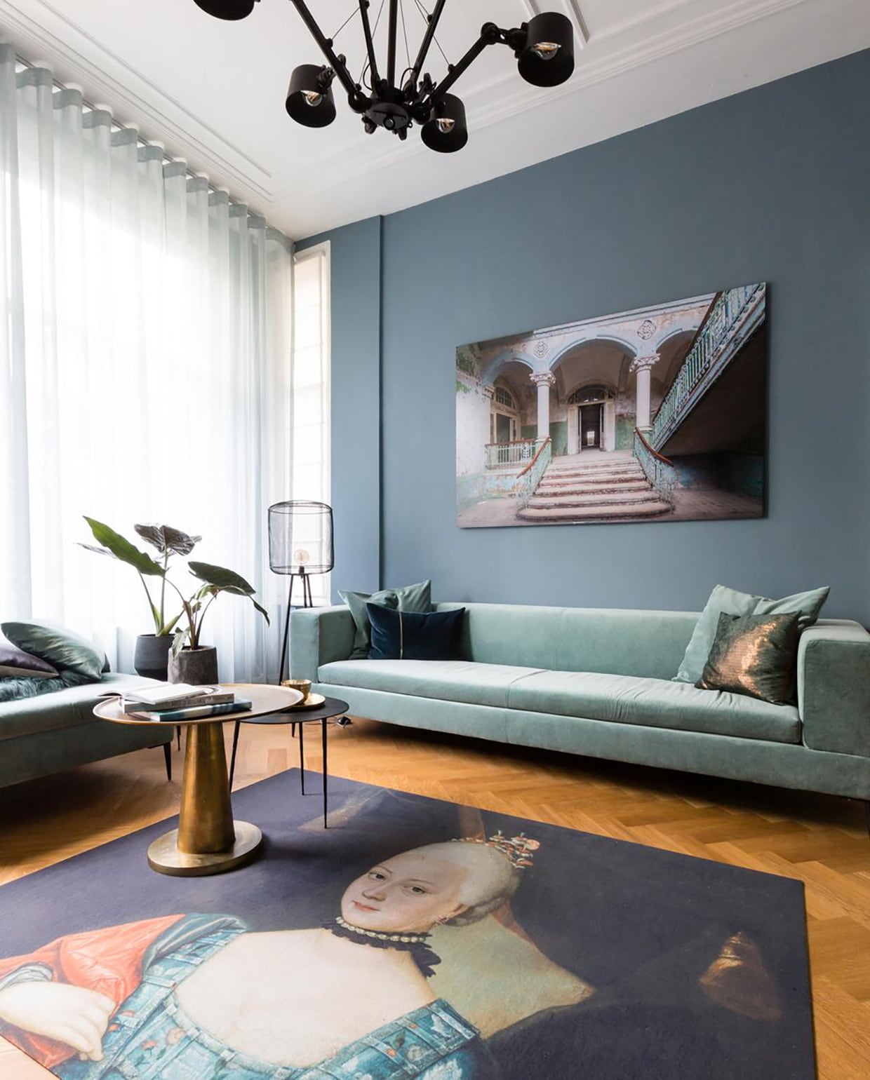 Kleur op de muur ‘Denim Drift’ . Gordijnen stof Adele kleur 210 . Vouwgordijnen stof Wooly kleur 10 . Kroonluchter . Vloerlamp Hikari . Tafellamp Hawk . Kunstwerk ‘De vervallen ingang van Beelitz’ . Vloerkleed . Bank  . Bijzettafel goud . Bijzettafels zwart . Poef ‘Piero’ . Schapenvacht . Kussens . Potten , Planten vtwonen weer verliefd op je huis | seizoen 11 aflevering 9 | fotografie Barbara Kieboom | styling Frans Uyterlinde