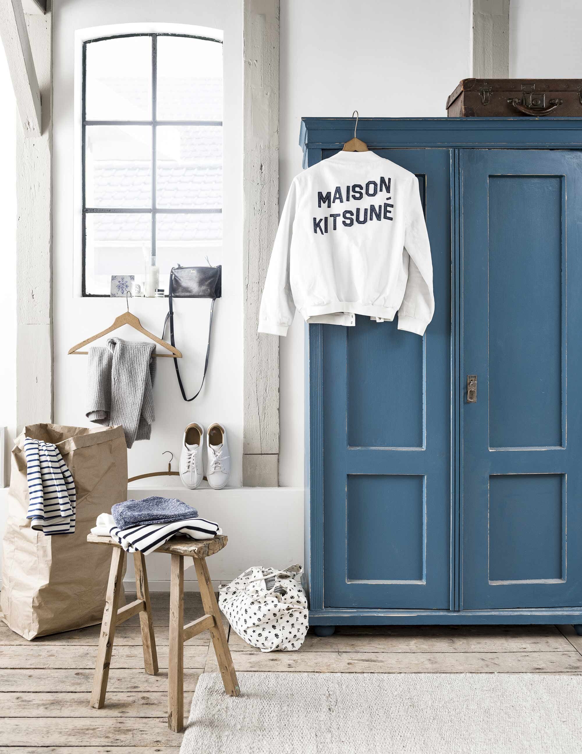 Blauwe kast, houten krukje (Van Dijk &amp; Ko). Bruine papieren zak, hier gebruikt als wasmand (vtwonen). Lichtgrijs vloerkleed (l’Etoile). Witte leren schoenen, gestreepte tops (Six and Sons). Overig privébezit.