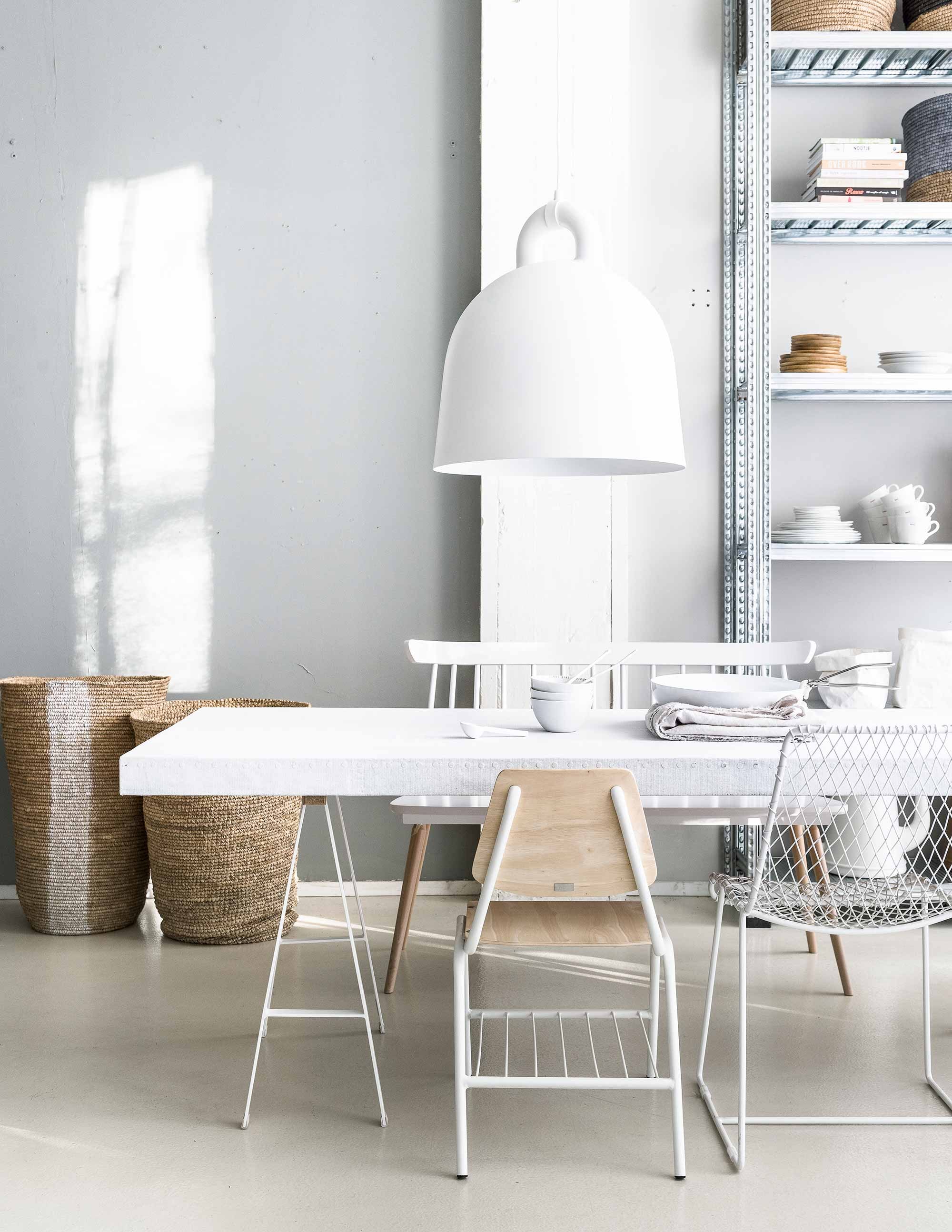 Op de muur krijtverf, lamp Large Bell van Normann Copenhagen, stoel van draadstaal, bankje, rieten manden, kleine mand, houten kommen (Loft). Tafelblad bekleed met doek (Combitex). Schragen, stoel met houten zitting van Studio Simple (Serax). Servies, papieren opbergzakken en stellingkast A La Carte p.o.a. (Transvorm). Linnen laken (House in Style). Pan en losse klem van KnIndustrie (Do’s). Porseleinen lepels (Serax).