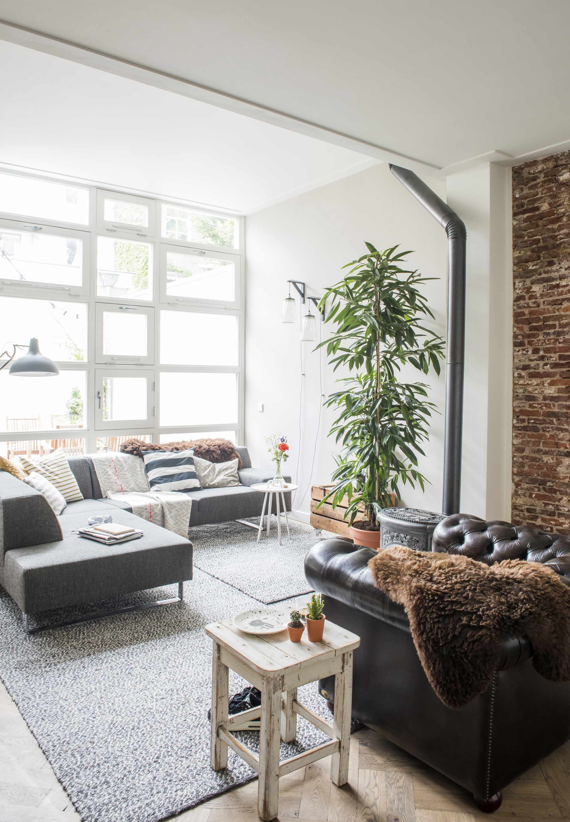 lichte woonkamer met grijze bank en vloerkleed