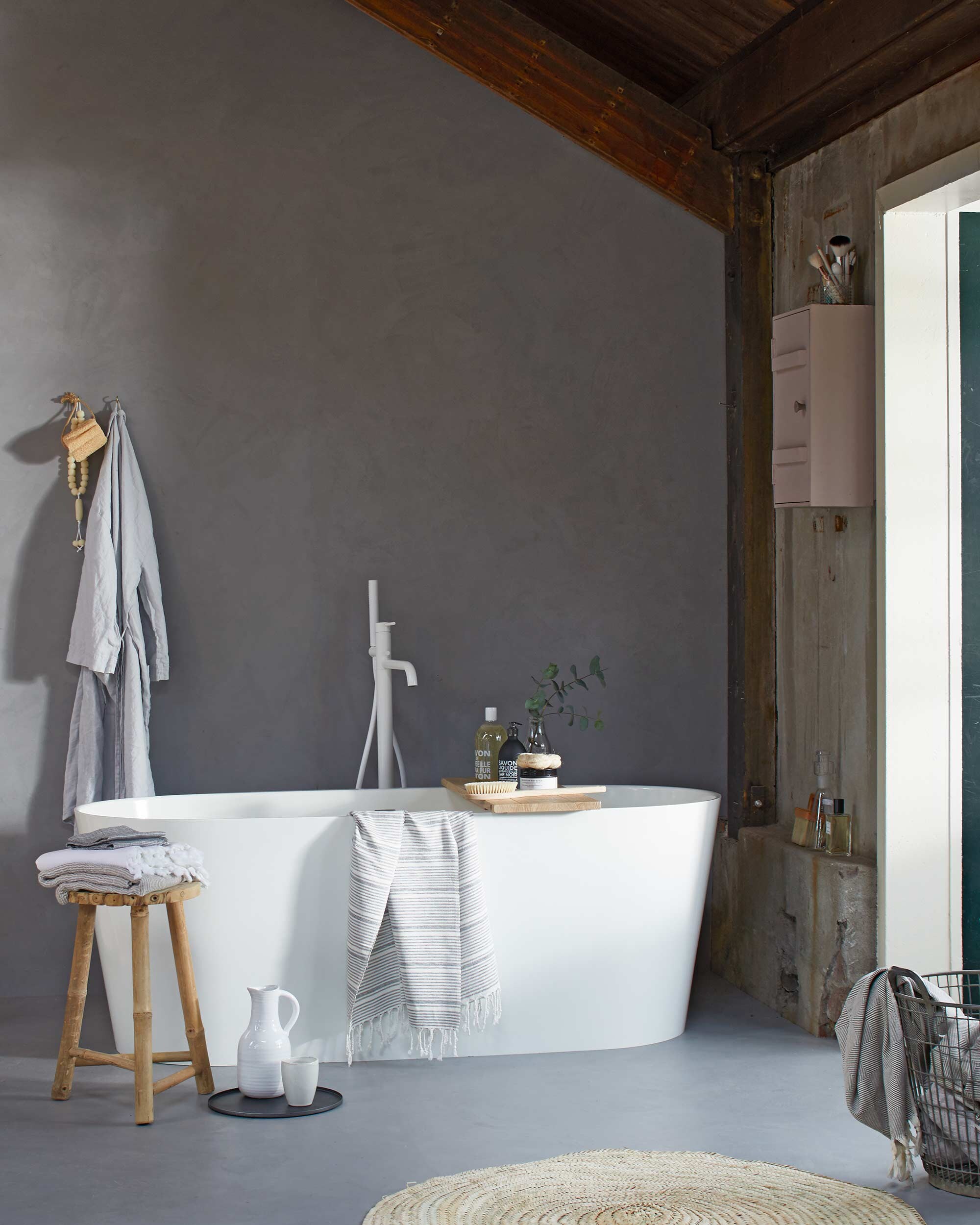 Op de muur en vloer: Basic Beton van vtwonen by Douglas &amp; Jones in de kleur Zinc, Bad Tub van gegoten marmer, Badplank Board van geolied eiken met geïntegreerd bakje, vrijstaande badkraan met doucheslang en handdouche Curve in powder white. Badjas (H&amp;M). Krukje, vloerkleed, gestreepte hamamdoek, witte beker (l’Etoile Conceptstore). Zeepketting, handdoeken op kruk en in mand (Ottomania). Badborstel, scrubspons (Dille &amp; Kamille). Kan, badproducten (&amp;Klevering). Mand (Raw Materials). Medicijnkastje (Van Dijk &amp; Ko). Overig privébezit. vtwonen 02-2017 |Styling Cleo Scheulderman | Fotografie Jeroen van der Spek