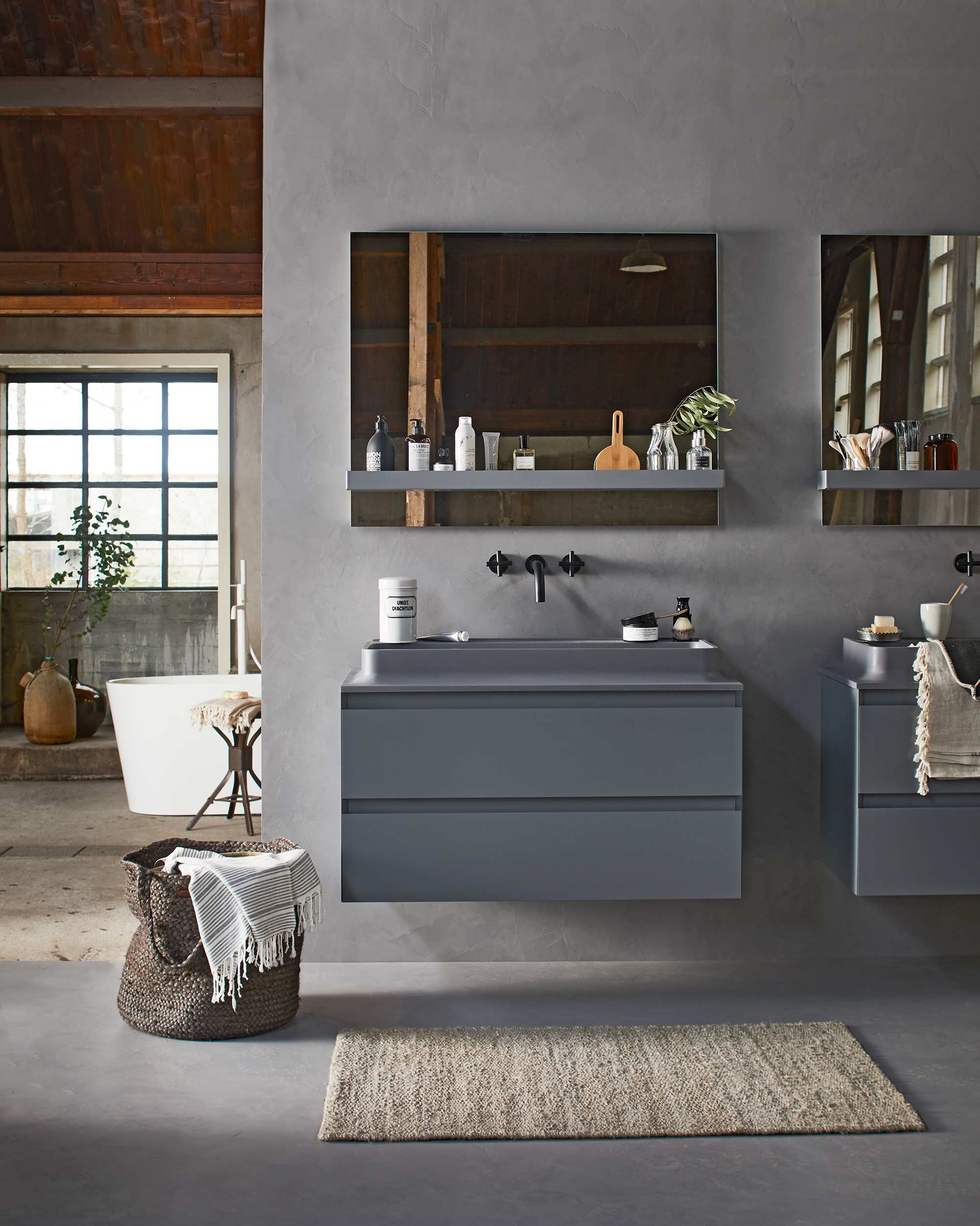 Op de wand en vloer: Basic Beton van vtwonen by Douglas &amp; Jones in kleur Zinc, spiegel Groove, planchet Groove in kleur graphite, kraan Cross in kleur charcoal, meubelwastafel Shell in kleur graphite, wastafelonderkast Shell met 2 lades in kleur graphite. Vloerkleed, gestreepte hamamdoek (l’Etoile Conceptstore). Mand (Hoffz). Zwarte scrub- washand, gastendoek op wastafel, zilverkleurig zeepbakje, zeepjes, hamamdoeken (Ottomania). Kruk (Neef Louis). Groene flesvaas (Raw Materials). Witte medicijnpot, canvas flesvaas (De Weldaad). Scheerkwast, badproducten (&amp;Klevering). Overig privébezit. vtwonen 02-2017 |Styling Cleo Scheulderman | Fotografie Jeroen van der Spek