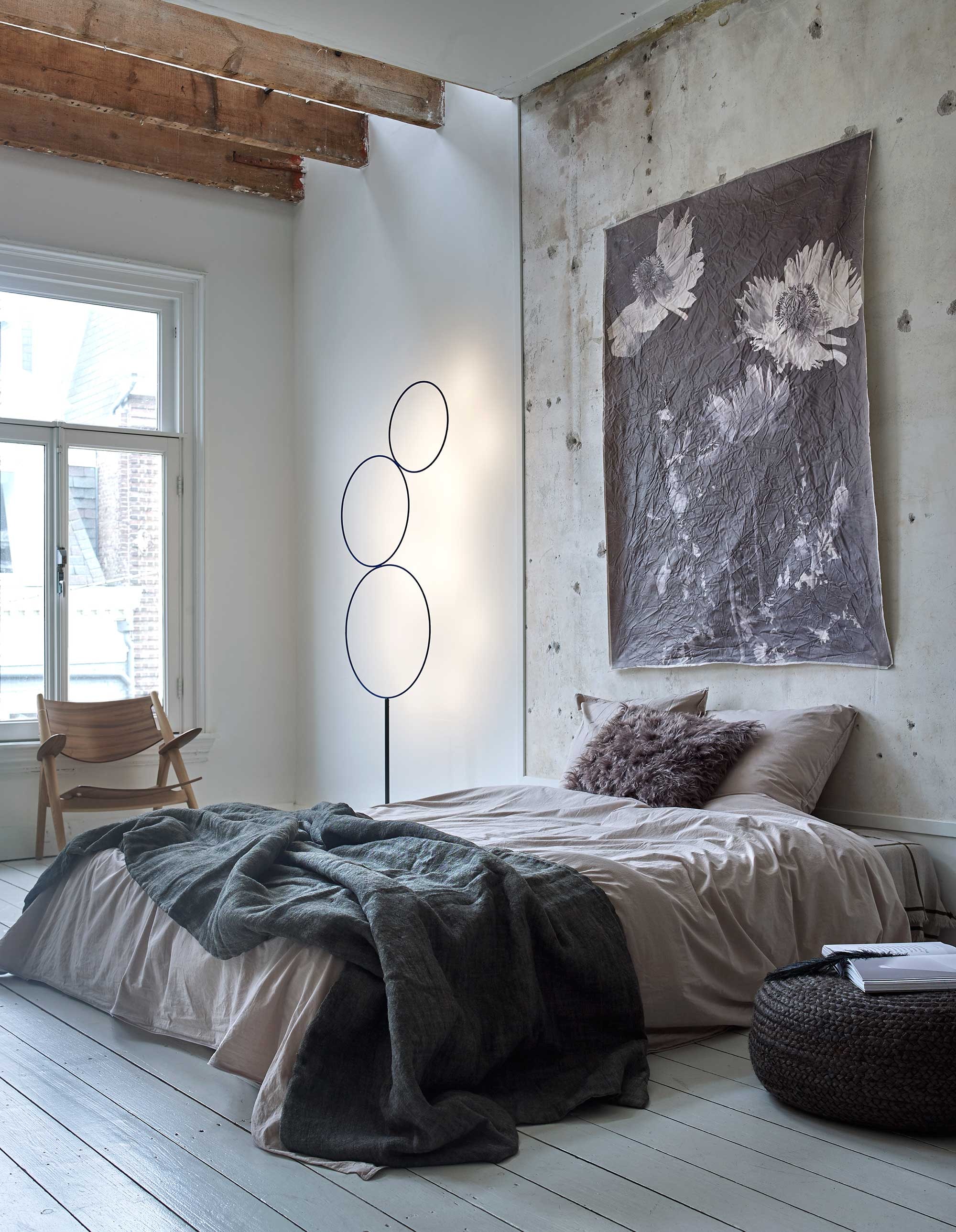 Dekbedovertrekset in katoen/perkal 240×220 cm met kussenslopen 60×70 cm, gevoerd grofgeweven jute/linnen sprei, 135×300 cm, harig kussen van mohair en linnen (Mrs. Me). Jute poef Ø 70 cm (Hoffz). Veer van Madam Stoltz (deens.nl). Canvas doek op de muur van Charles Aubry, afbeelding via mijn Rijks Studio, 130×170 cm (More than Canvas). Stoel in walnoot- en eikenhout van Hans J. Wegner, lamp van Catellani &amp; Smith (Mobilia).