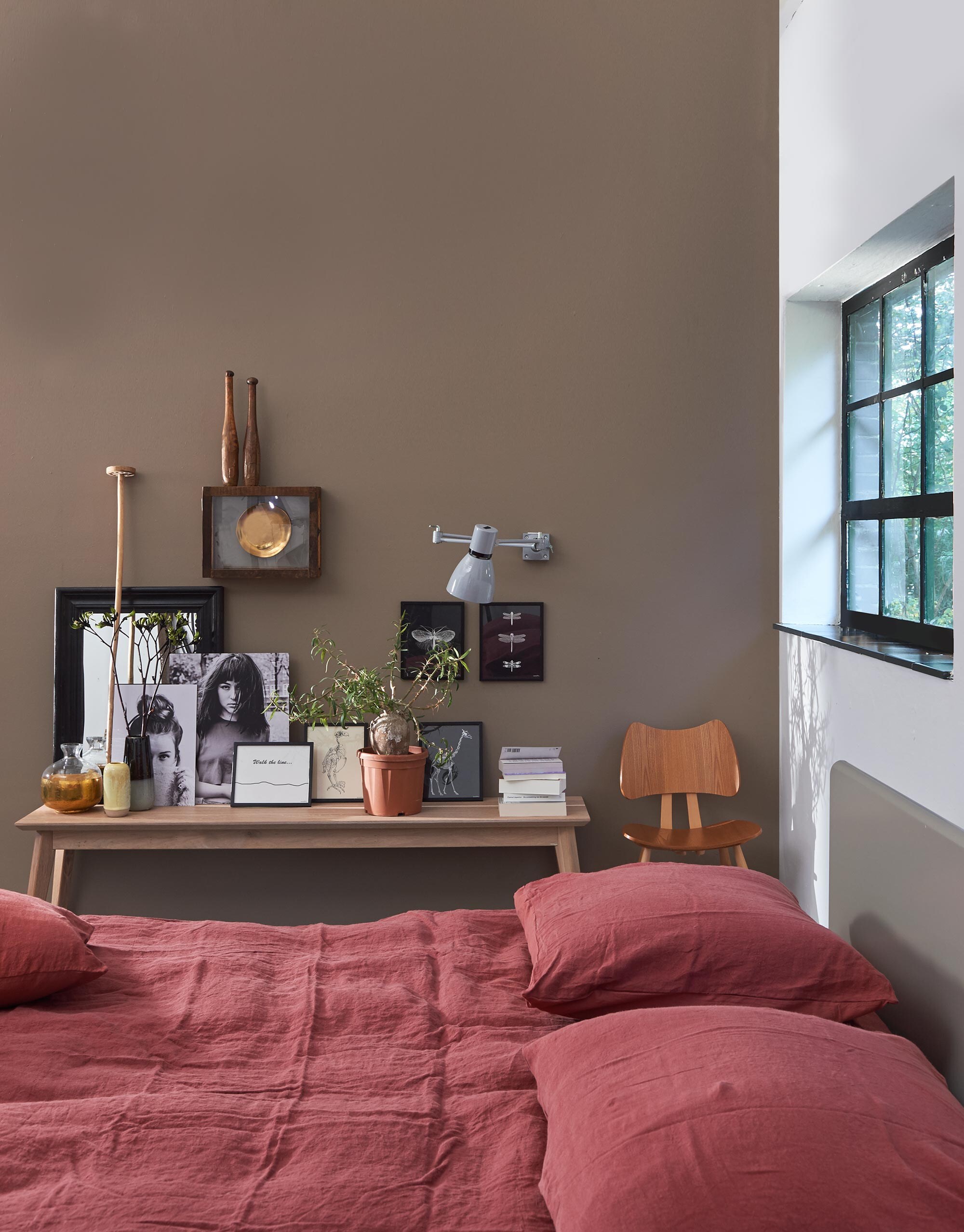 Bed Basket, gelakt in steengrijs (Loof). Linnen beddengoed (Vandyck). Lage bank Gunni, stoel Ercol Butterfly chair 401, wandlamp (De Machinekamer). Vitrinekastje, kegels per stuk, ingelijste posters (Raw Materials). Spiegel (De Weldaad). Zwart-wit foto’s (Loods 5). Vaas met goudkleurige onderkant (Store Without a Home). Geel vaasje (Six and Sons). Houten stamper (Burbri). Muurverf kleur Mire van vtwonen by Graham &amp; Brown (uitverkocht) (vtwonen.nl).