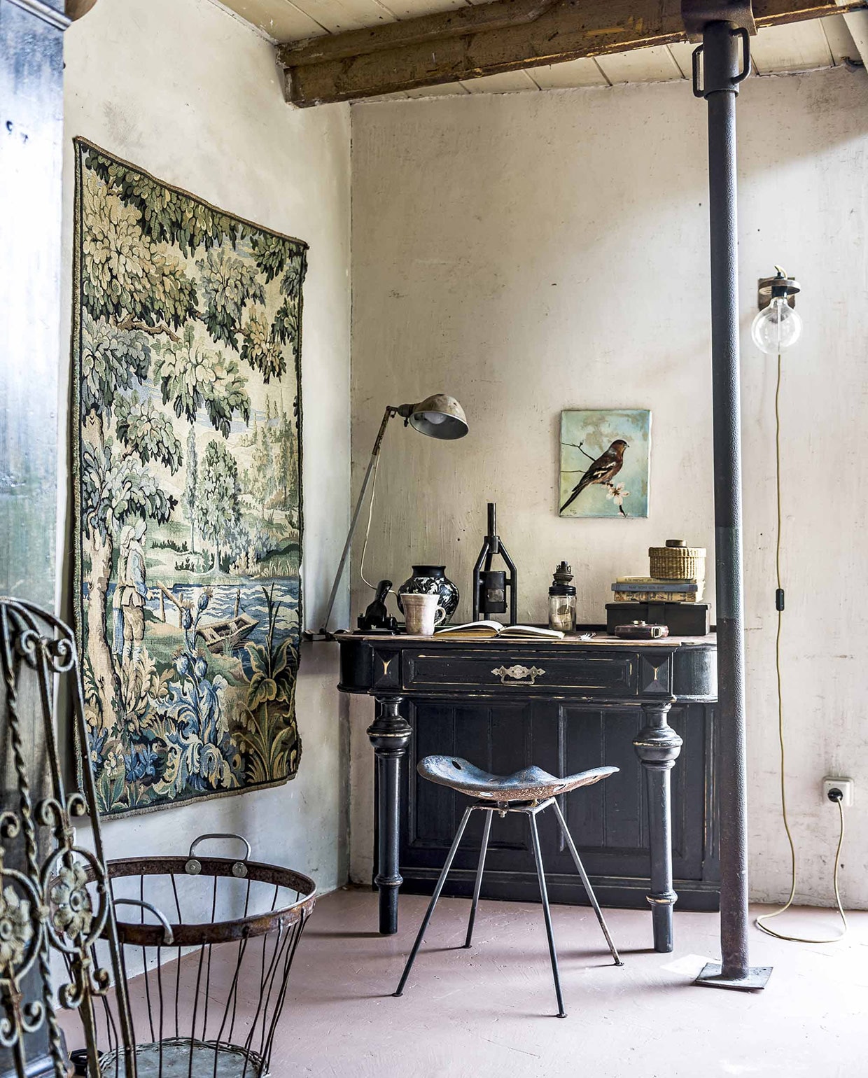 Wandkleed, zwart bureau (). Vintage designkruk, beker (). Bureaulamp, minikacheltje (). Geldkist (). Vaas ). Metalen draadmand (). Kantoorbenodigdheden, rieten mandje op bureau van een kringloopwinkel, overig privébezit. vtwonen 10-2016 | Fotografie Sjoerd Eickmans | Styling Liza Wassenaar