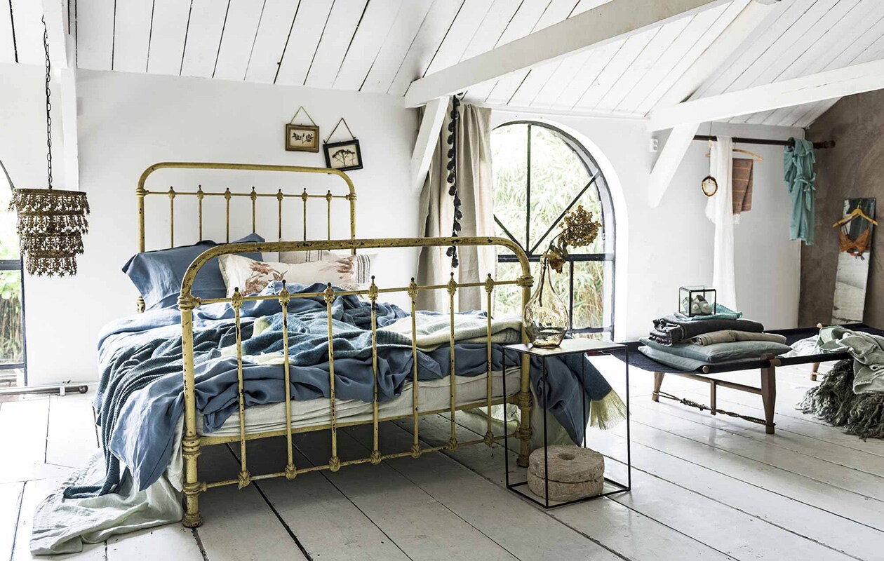 Hanglamp, laken van Society, kussen met bloemmotief, bellenkoord-, spijlenbed (), achter bed: lijstjes met gedroogde bloemen (). Linnen dekbedovertrekken in kleur old denim, bijpassend kussensloop, kelimkussen (). Zelfgemaakt kussen met bloemen van oude gordijnstof. Gestreepte plaid van Malagoon (). Grove plaid van gerecycled denim, zwart daybed van onbehandeld berkenhout, ongeverfd linnen en sisal (). Voor het bed: ijzeren bijzettafel (), vaas (), molenstenen privébezit. Op daybed: glazen kistje, babyslofjes van , stonewashed grijze plaid (), mintgroene kussens (), geborduurd laken, prijs op aanvraag (), andere stoffen privébezit. Opgevouwen kleed van schapenvacht, kunstwerk van steen en kristal (), jadegroene linnen plaid (). Linnen sjaal (), hammamdoek van linnen en bamboe (). Spiegel (kringloop), beha (), kimono (). Spiegel tweedehands., vtwonen 10-2016 | Fotografie Sjoerd Eickmans | Styling Liza Wassenaar
