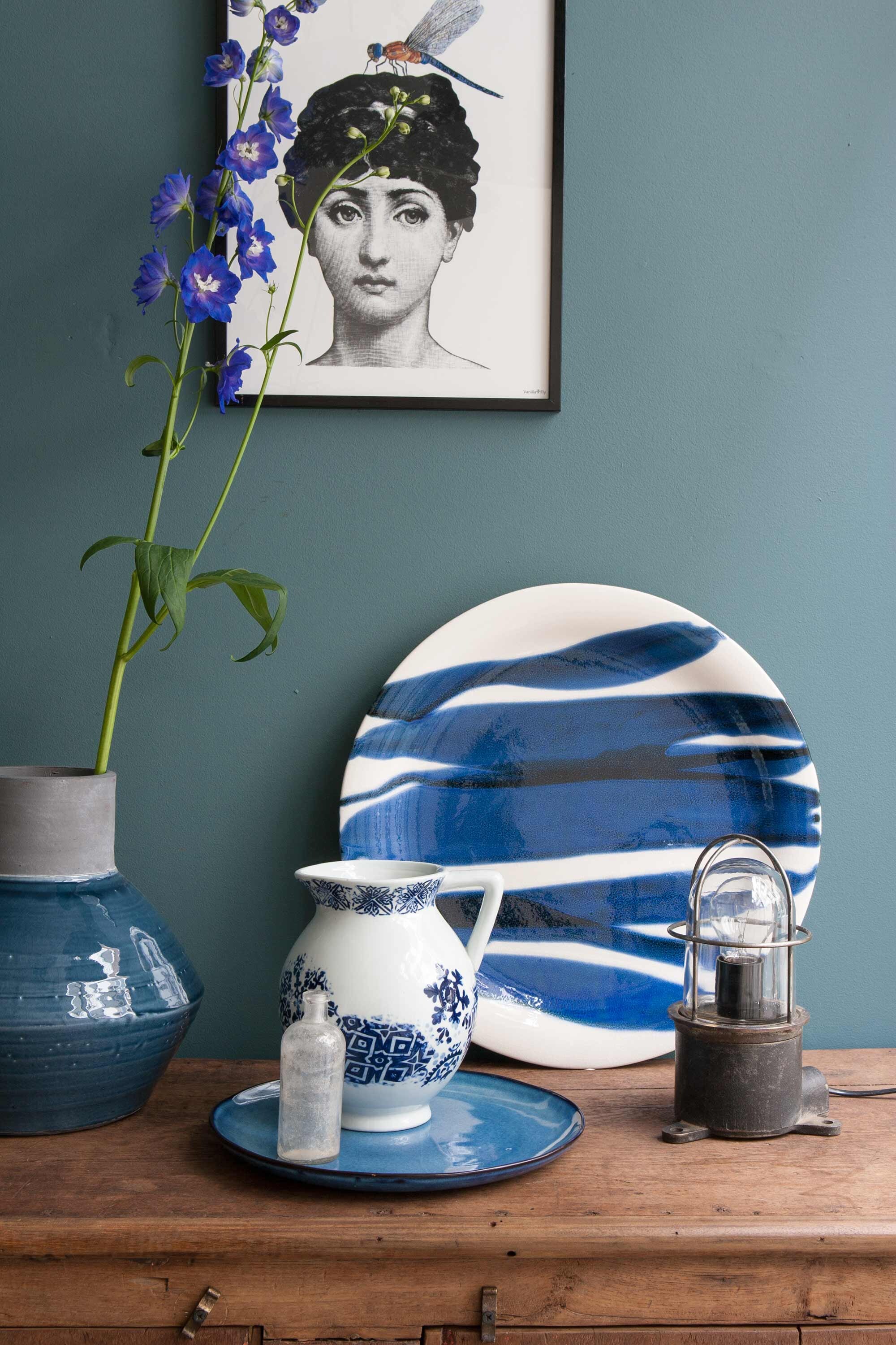 Dressoir, lamp, lijst met afbeelding vrouw, flesje (). XL bord met dessin van Pomax, bord, vaas, schenkkan ().