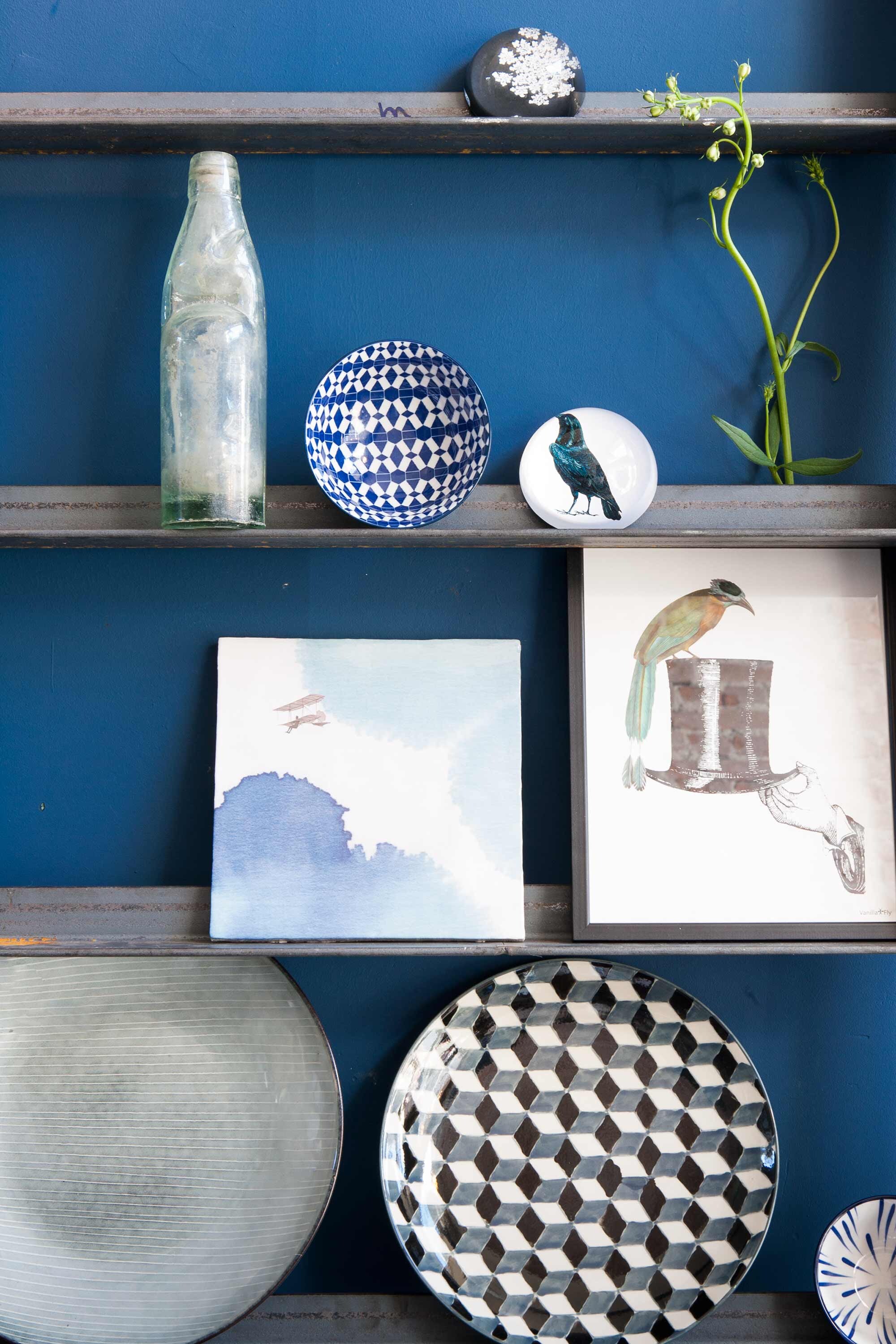 Bordenrek van staal (). Vergrijsd blauw bord, kommetjes met dessin (). Tegel van StoryTiles, bord met kubusprint set van vier (). Fles, presse papier vanaf, lijst met afbeelding hoed ().