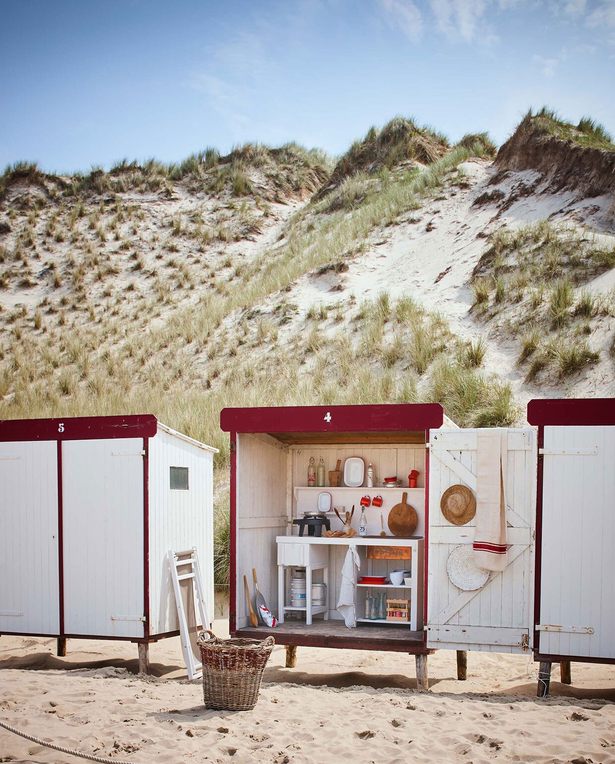 Keuken vanaf (). Bollenmand, strandstoel Alpina, emaillen bekers met oor, emaillen schalen set, grote rechthoekige emaillen schaal, emaillen kommen, kleine bekers, oude waterflessen (). Aluminium thermosfles, pannetjes (). Oude linnen lap met rode strepen (). Grote houten lepel, witte rieten schaal, houten vijzel, theedoek (). witte emaillen kommen (). Hoed (). Fles drinken van Nicolas Vahé (). Overig privébezit. Strandhuisjes te huur via . vtwonen 08-2016 | Fotografie Jeroen van der Spek | Styling Cleo Scheulderman