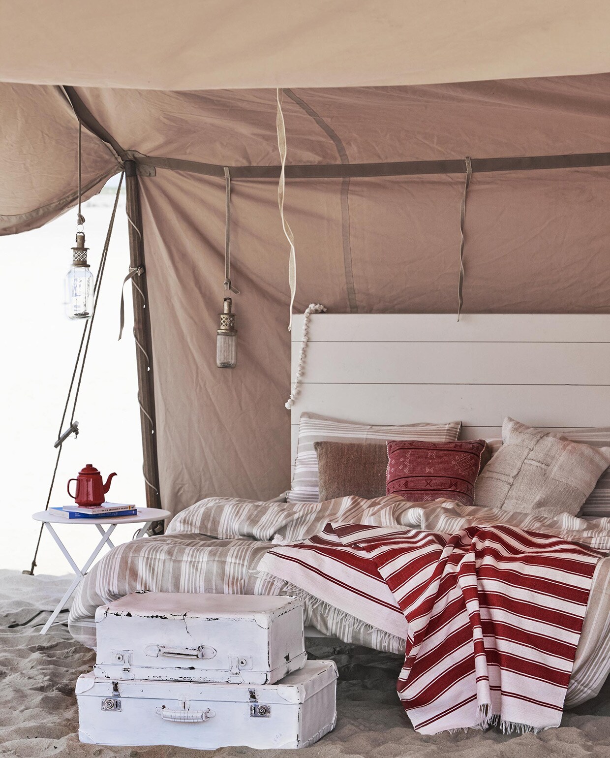 Houten bed (). Witte koffers (). Rood-witte doek vanaf ().  Tom Pouce van Fermob, emaillen theepot (). , vlaskleurig kussen (). Gestreept linnen dekbed-overtrek Sahara en kussenslopen Sahara (). Rood geborduurd kussentje (). Wit patchwork kussen (). vtwonen 08-2016 | Fotografie Jeroen van der Spek | Styling Cleo Scheulderman