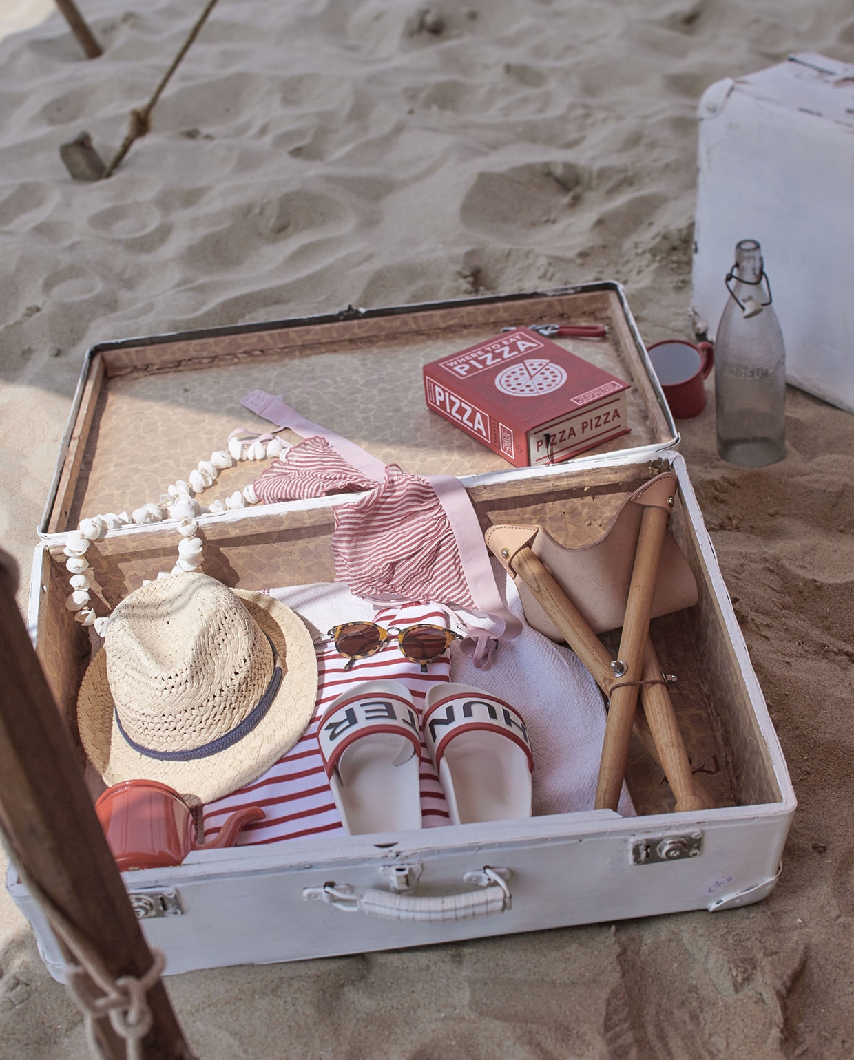 Koffer (). Slippers, Pizza boek, hoed (). Emaillen theepot, emaillen beker, oude fles (). Ketting (). Rood met wit gestreepte Bretons T-shirt en opvouwbare kruk (). vtwonen 08-2016 | Fotografie Jeroen van der Spek | Styling Cleo Scheulderman