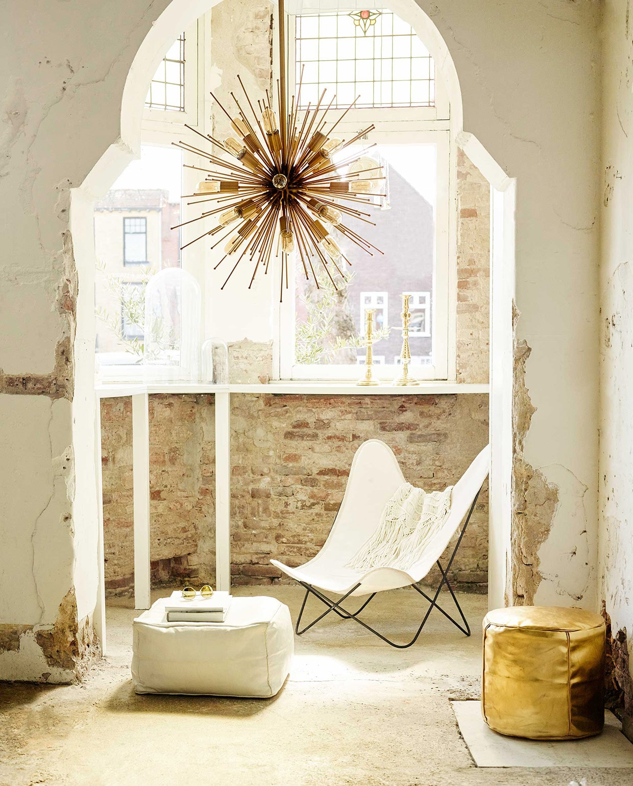 Lamp van Madam Stoltz (Deens). Vlinderstoel, witte leren poef, goudkleurige poef, goudkleurige kandelaars (Household Hardware). Vestje met franjes (H&amp;M). Bril met goudkleurige spiegeling (Saraghina Eyewear). vtwonen 07-2016 | Fotografie Tjitske van leeuwen | Styling Marianne Luning