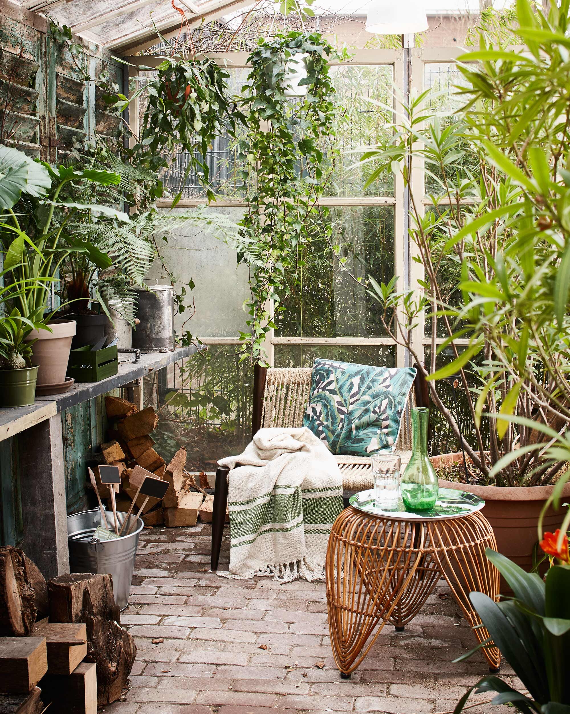 Stoel (Madam Stoltz). Kruk (l’Etoile Conceptstore). Kussen Tropical Banana Leaf green (Livv Lifestyle). Dienblad met bananenblad, groen kratje, plaid (H&amp;M Home). Groene glazen karaf (Household Hardware). Zinken emmer, plantenetiketten, groen metalen plantenpotje, oude metalen voorraadbussen (Combitex). Overig privébezit.