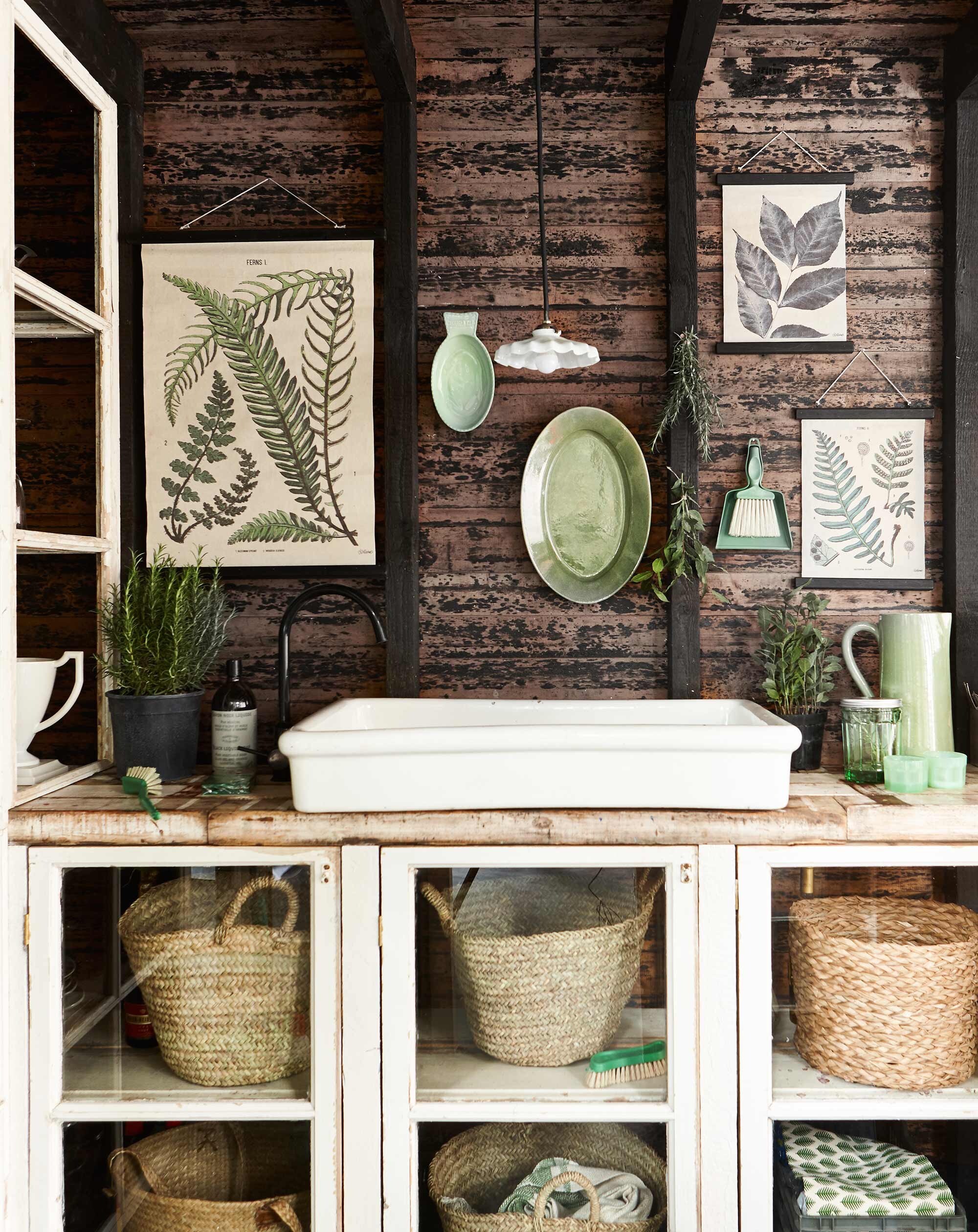 Botanische prent van canvas, botanische prent (HK Living). Ovale schaal, groene kan (De Weldaad). Manden in kast (Household Hardware). Groene glazen visvormige schaal, groene glazen pot met deksel, alles uit de collectie van Paola Navone (Serax). Groene stoffer en blik, groene afwasborstel, groene schrobborstel (l’Etoile Conceptstore). Fles zeep (Dille &amp; Kamille). Hanglampje en overig privébezit.
