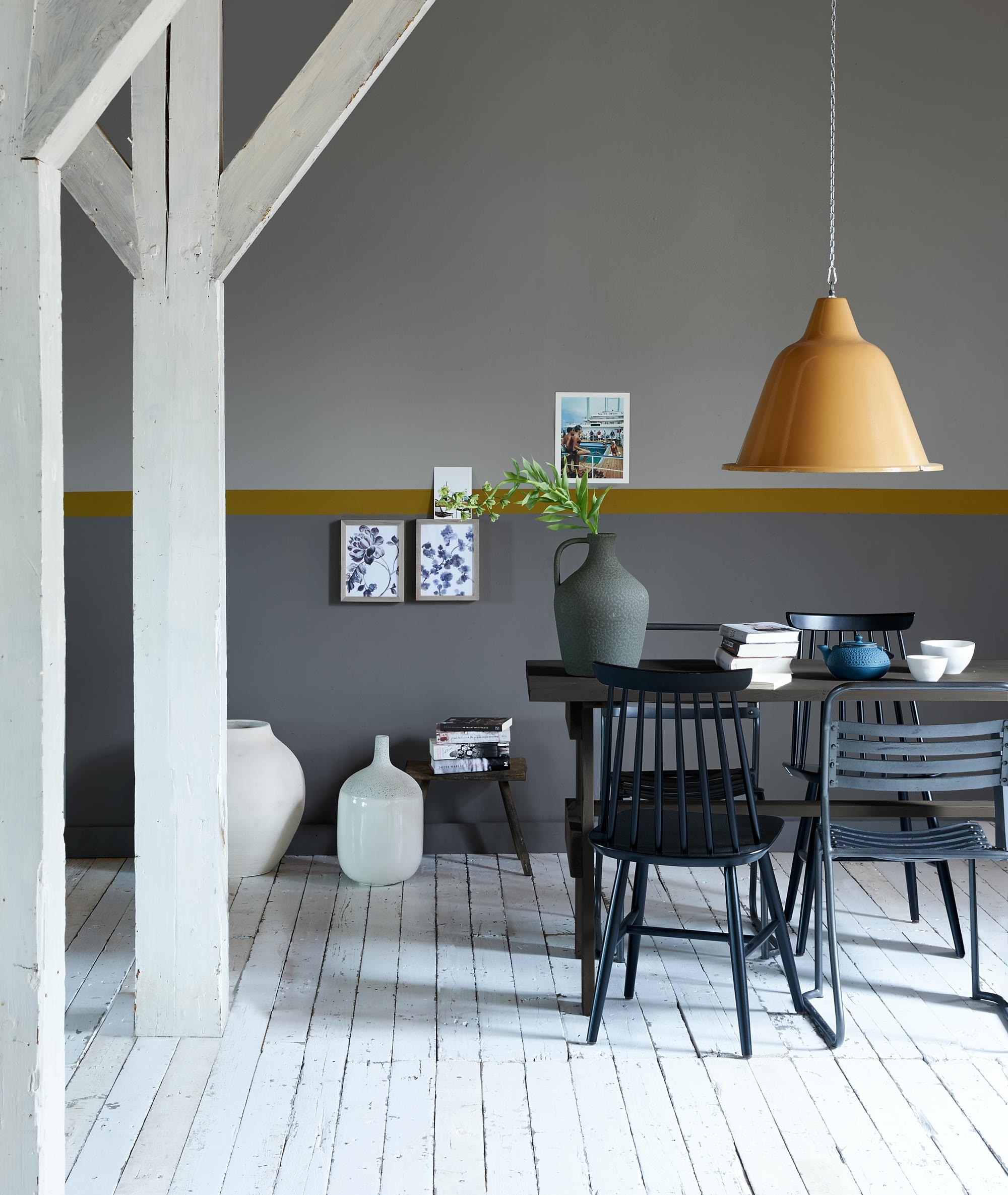 Verfkleur wand boven: ash grey, verfkleur rand: forest, verfkleur wand onder: concrete, verfkleur tafel: mud grey. Lamp (Neef Louis). Eetkamerstoelen (Het Kabinet). Tafel (Combitex). Witte vazen op de vloer, donkere vaas op tafel (Casa Vivante). Ijzeren theepot, mok, kom (Loods 5). Overig privébezit. vtwonen