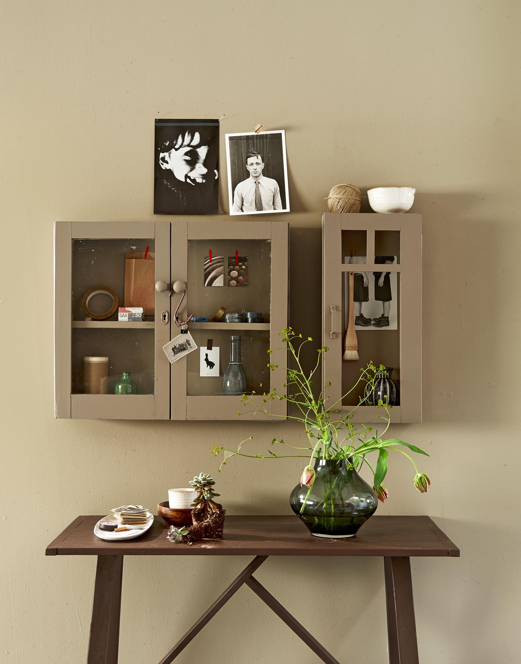 Verfkleur wand: warm grey, verfkleur kastjes: mire, verfkleur tafel: warm brown. Kastjes, tafel (Combitex). Vaas, ovaal wit bord, houten kom (Loods 5). Vaasjes in de kast, witte mok, witte kom (Casa Vivante). Kwast in kastje (Vlieger). Overig privébezit. vtwonen