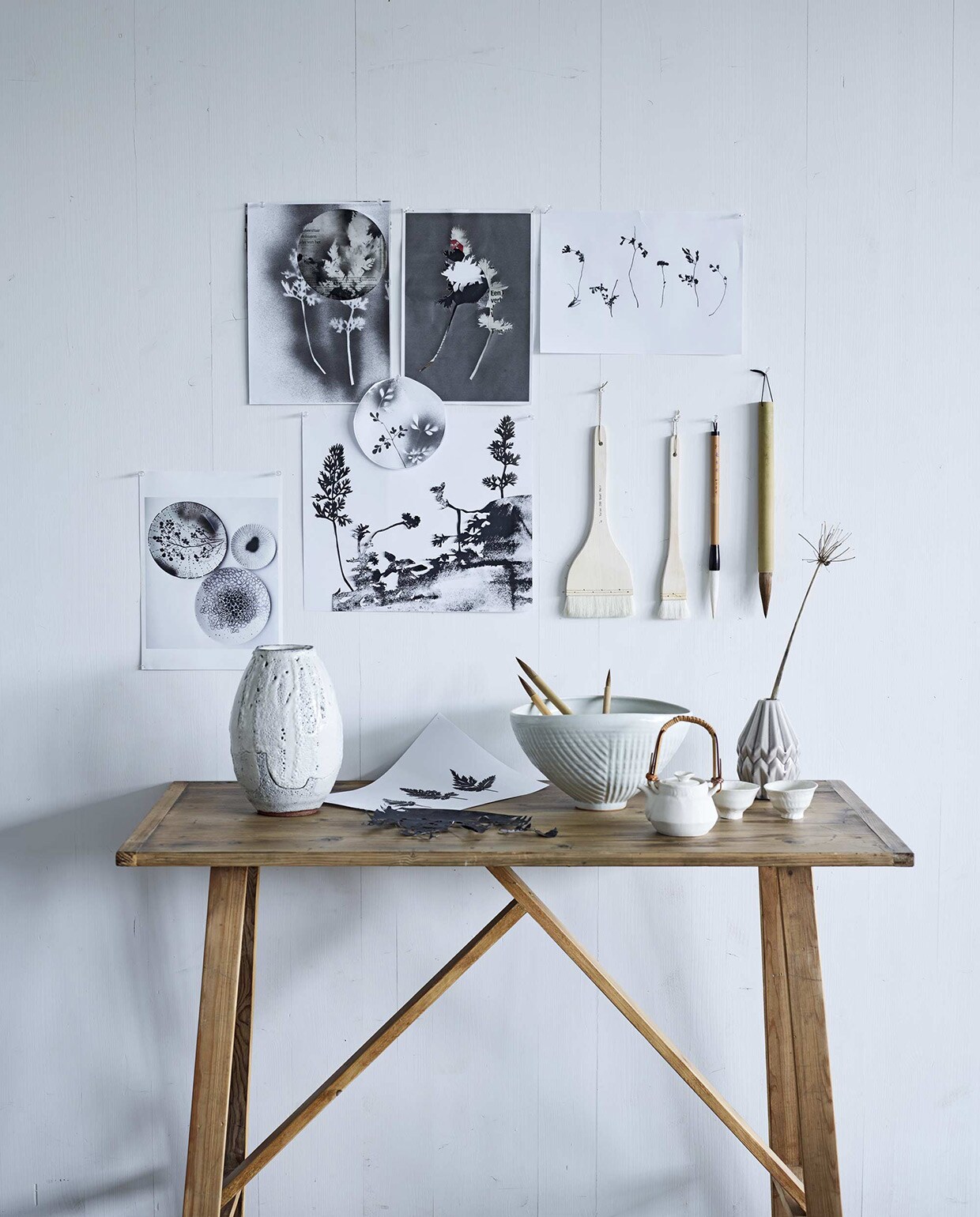 Aan de wand grafisch werk van Hedwig van Onna (). Sidetable (). Erop v.l.n.r. vaas Ogama, schaal, theeset bestaand uit een pot en twee bekertjes, penselen (). Kwasten (). Gevouwen vaasje ()., vtwonen 05-2016 | Fotografie Jeroen van der Spek | Styling Fietje Bruijn