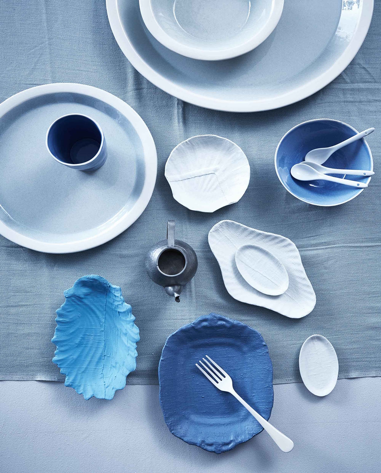 Voorste porseleinen schaaltjes in blauw en wit, handgemaakt en gedecoreerd met een speciale techniek (). Grote schalen vanaf, beker, blauwe kom (). Porseleinen lepels (). Witte geëmailleerde  (Nordal). Loper van Youyou (. Tinnen theepotje privébezit. vtwonen 05-2016 | Fotografie Alexander van Berge | Styling Cleo Scheulderman