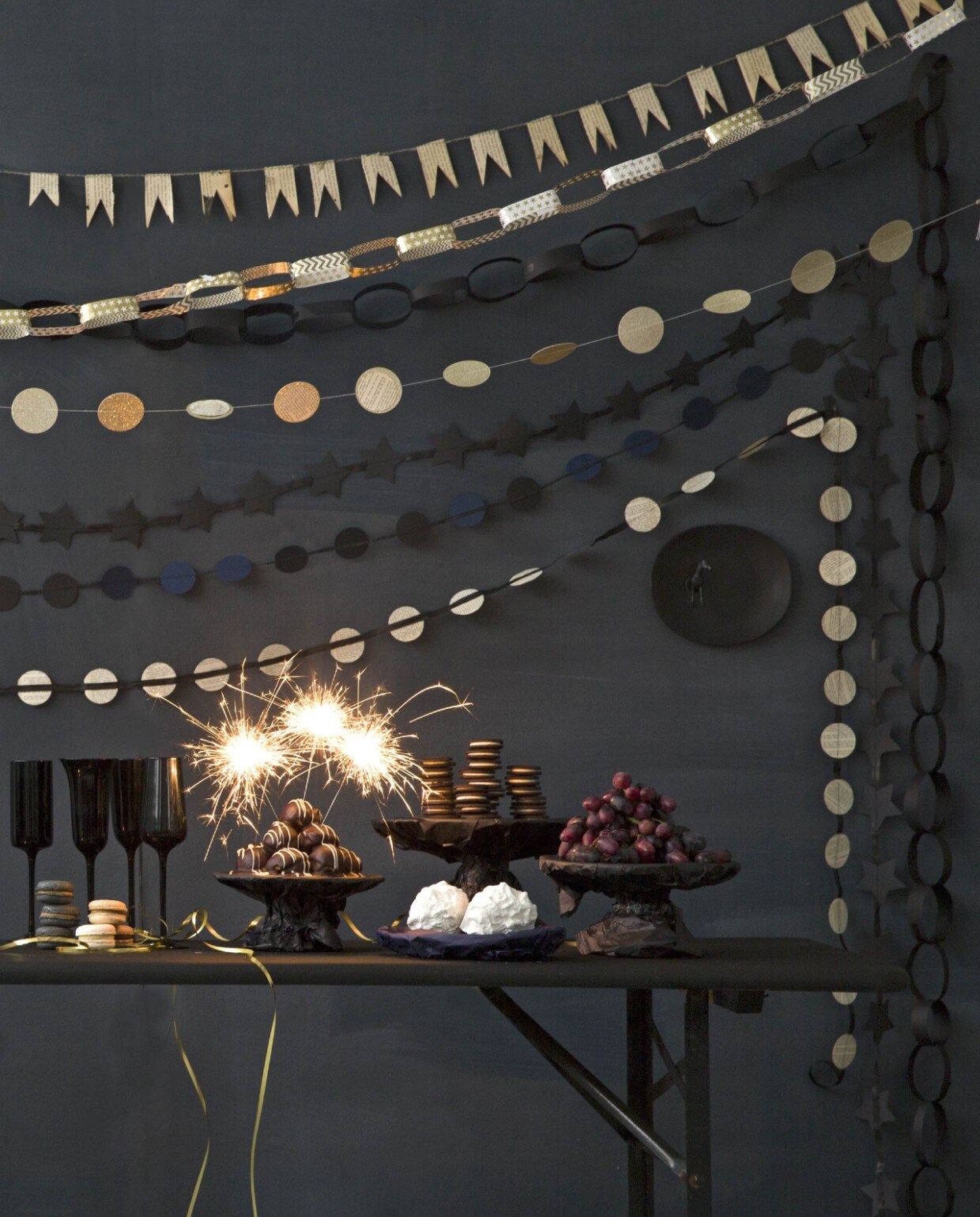 De muur is geschilderd in kleur Squid Ink van Bauwerk Color (AnoukB). Kruk van zwart draadstaal van Evenaar (Loods 5). Champagneglazen van Desigual, zwart glas (Bitossi Home). Bolvaasje zwart (Action). Goudkleurig waxinelichtje (H&amp;M). Fles met zwart reliëf (kringloop). De klaptafel is geverfd met zwarte krijtverf (Action). De taartschalen van de kringloop zijn ingepakt met vloeipapier. Macarones van Patisserie Tout in Amsterdam. Profiterolles en schuimbollen van Banketbakker Vlaar in Haarlem.