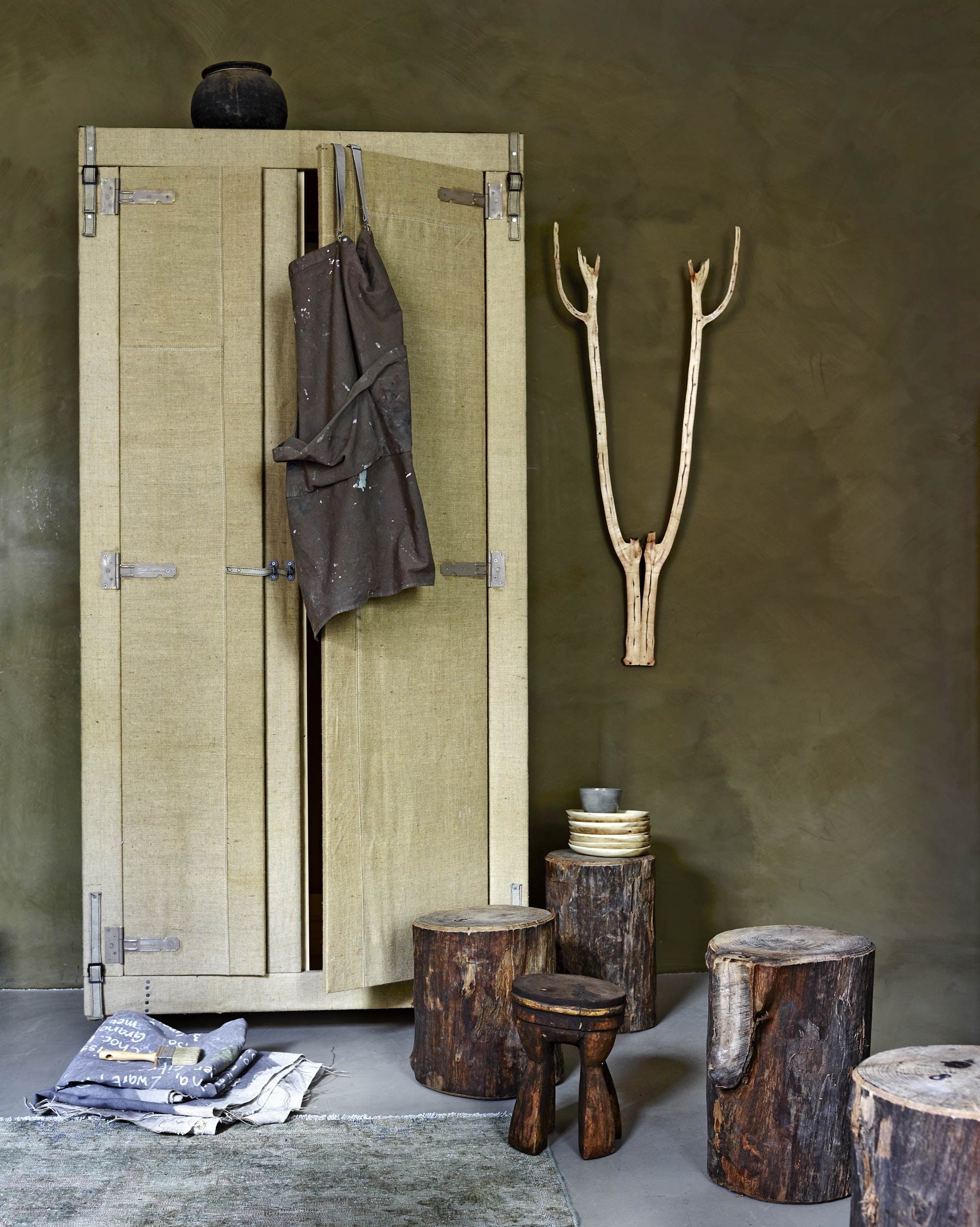 Kast bekleed met jute (Combitex). Verf Hawtorn uit de Limestone collectie van Bauwerk, canvas schort, boomstammen, gewei van Geweldig Gewei, bamboe schaaltjes, kom van keramiek, Frans linnen, kwast (AnoukB). Houten krukje (Hoffz). Oud Perzisch karpet (Ebru).