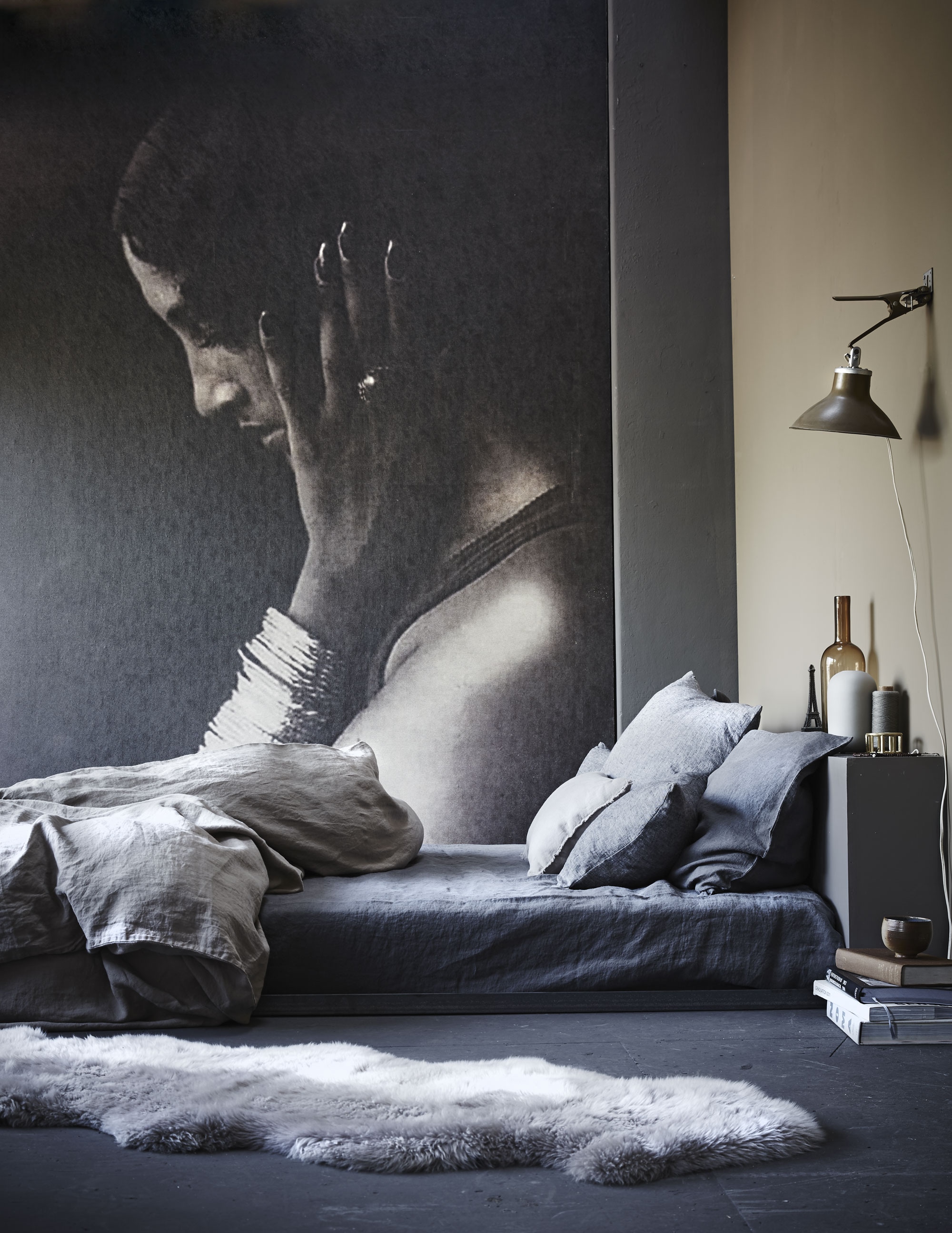 Op maat gemaakt fotobehang (www.bnwallcoverings.com). Het hoofdeinde van het bed is ook op maat gemaakt (Combitex). Hoeslaken van linnen, kleur antraciet, 160×200 cm, dekbedovertrek 220×240 cm, linnen kussensloop 50×70 cm (Couleur Locale). Lichtere grijze linnen kussens van By Molle, kleur houtskool, 60×60 cm, 40×60 cm (vtwonen.nl). Wandlamp (Spoor 38). XL schapenvacht (www.tapijtenenhuiden.com). Op het hoofdeinde: Eiffeltoren (Spoor 38), amberkleurige flesvaas (Friday Next), lichtgrijze vaas van Asa (vtwonen.nl), messing armband (Restored). Kom op boeken (Six and Sons). Overig privébezit.