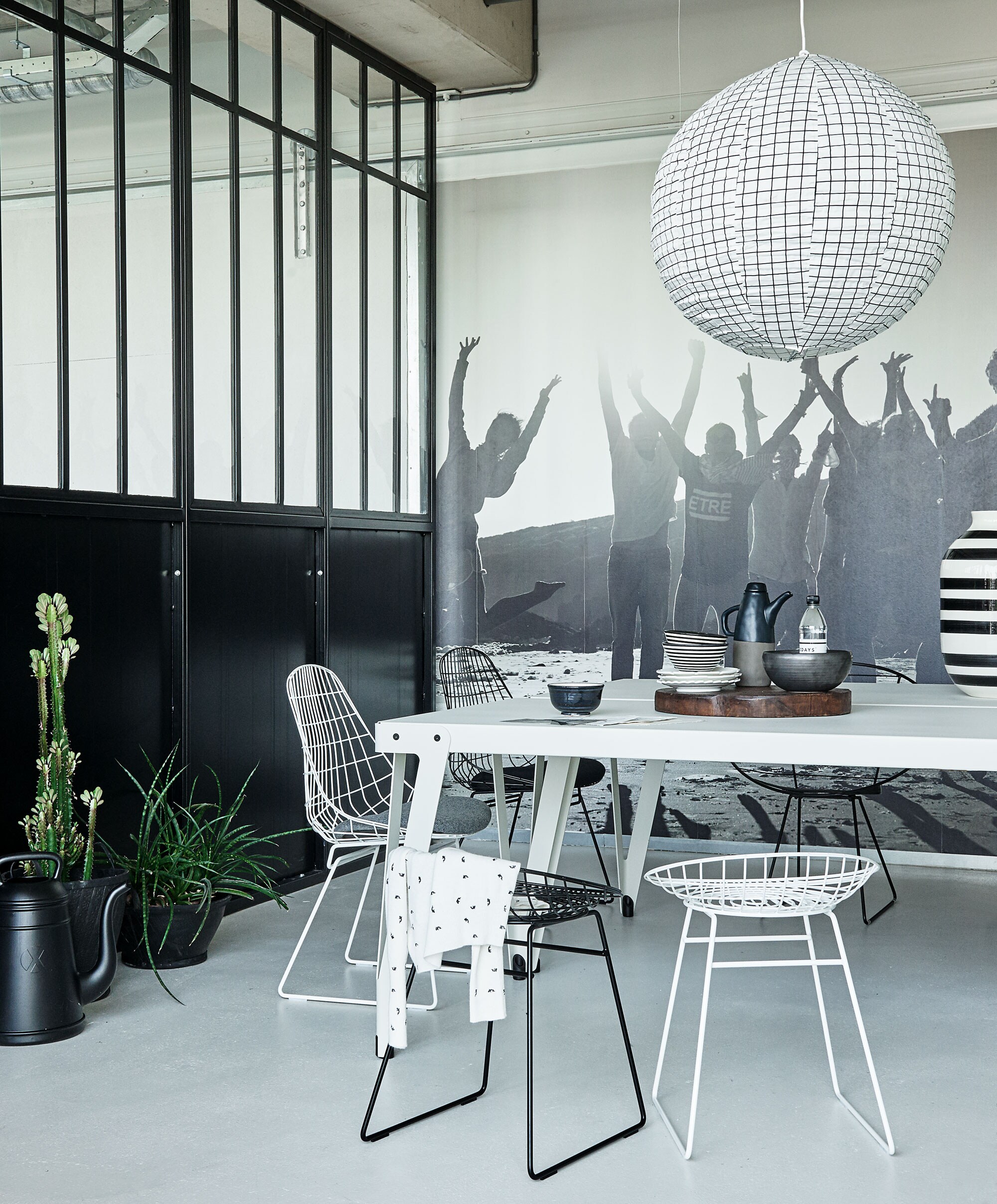 Witte metalen tafel Lloyd in gepoedercoat staal (Functionals). Metalen kruk Wire in zwart en wit van Pastoe, Witte metalen stoel met kussen van Pastoe, Zwarte metalen tuinstoel Happy van Nordal, Zwarte gieter Xala Lungo (vtwonen.nl). Rubberen manden van (Household Hardware). Stoffen hanglamp, zwart-witte vaas (&amp; Klevering). Houten plateau, zwarte schaal, witte bordjes van Diesel per set van 4, zwart-witte schaaltjes van Tine K Home, zwart schaaltje van Tine K Home, theepot (Nijhof). Illustratie prijs op aanvraag (maartjevandennoort.nl). Fotobehang gemaakt van een foto uit de 10 Days catalogus (Hema). Vest (10Days). Planten privébezit.