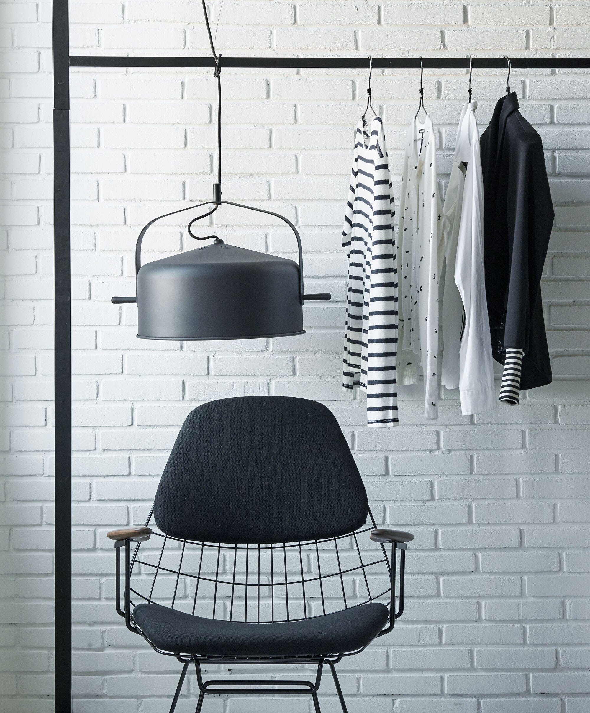 Zwarte stoel Wire lounge chair van Pastoe (hxbxd), zwarte hanglamp Bombay van It’s about Romi (vtwonen.nl). Kleding (10Days). Rek privébezit.