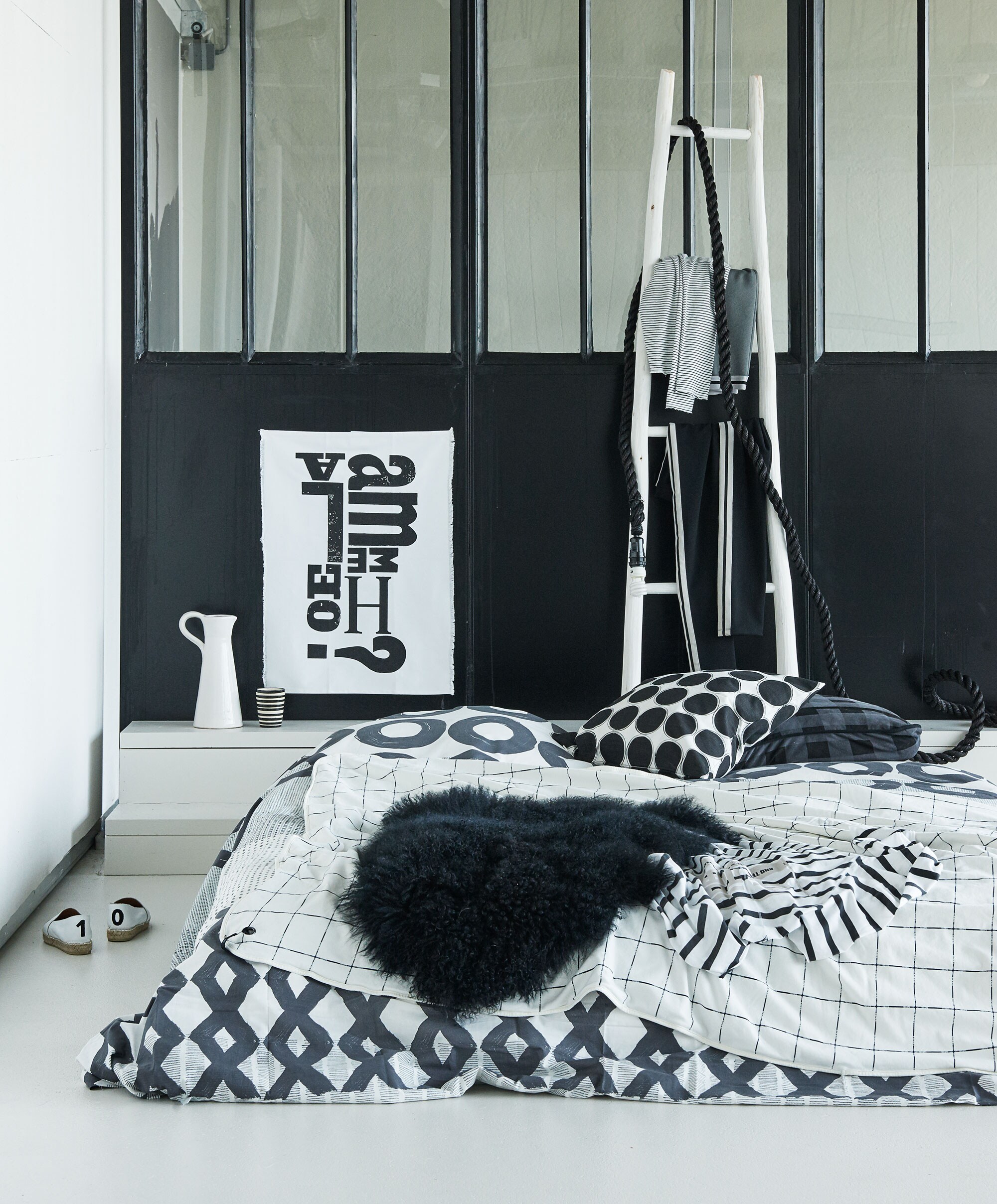Beddengoed incl. kussenhoezen van Tinne + Mia, canvas poster Ammehoela 50×70 cm, touwlamp HK Living (vtwonen.nl). Kussenhoes met stippen (H&amp;M), Zwarte schapenvacht Bloomingville (Nijhof). Ladder, kan, mok, (Household Hardware). Geruit plaid van jersey katoen, zwart-grijs geblokt kussen, kleding (10Days). Schoenen privébezit.