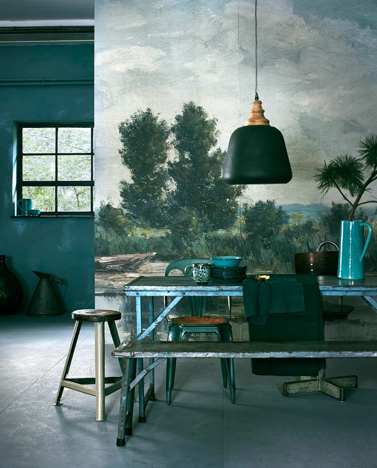 Behang op basis van Plas bij Loosdrecht van Willem Roelofs, gedownload uit het archief van het Rijksmuseum. Het fotobehang werd op maat gemaakt, (www.bnwall-coverings.com). Muurverf rond het raam Pure &amp; Original Classico krijtverf, kleur Blue Reef (De Ru). Smalle tafel Market table, vouwbankje (Raw Materials). Turkooise stoel Forbach, stoel met kruisvoet (Brût Amsterdam). Kruk (Combitex). Ontbijtborden, kom (Serax). Tafellaken, servet (H&amp;M). Hoge geglazuurde kan, kan in raamkozijn; kom (In Petto). Op de grond: groene fles, oliekan (Raw Materials). vtwonen 11-2015 | Fotografie Jeroen van der Spek | Styling Cleo Scheulderman