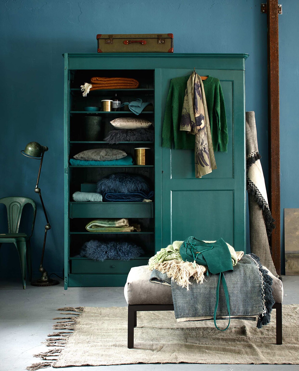 Stoel Forbach, Jieldé lamp Lille koffer (De Weldaad). Kast (Combitex). Vergelijkbare verfkleur: Duizendblad (Histor). In de kast: okergele en blauwe plaid op plank 1 en 5 (Dynamic Comfort). Kom (Serax). Messing pot met marmeren deksel (Madam Stoltz). Apothekersfles (De Weldaad), linnen kussensloop, olijfgroen dekbed (Couleur Locale). Pot (Raw Materials). Beige fluwelen kussen (H&amp;M). Schapenvachtkussens op plank 3 en 5 (Nordal). Grijs canvas kussen (Aai Made With love). Linnen dekbedovertrek (Couleur Locale). Messing pot (Madam Stoltz). Mohair plaid in pastelgroen (De Weldaad). Schapenvacht (Nordal). Aan de deur: trui van Rue Blanche (Sukha Amsterdam). Sjaal (Maison NL). Tegen de kast: vloerkleed (Aai made with love). Poef City bekleed met fluweel (vtwonen.nl). Daarop: ketting, tas (Sukha Amsterdam). Groene plaid (De Weldaad). Beige plaid, grijs vloerkleed (Aai made with love). Vloerkleed 220×135 cm (Raw Materials). Muurverf Pure &amp; Original Classico krijtverf Libo Bay, (De Ru). Overig privébezit. vtwonen 11-2015 | Fotografie Jeroen van der Spek | Styling Cleo Scheulderman