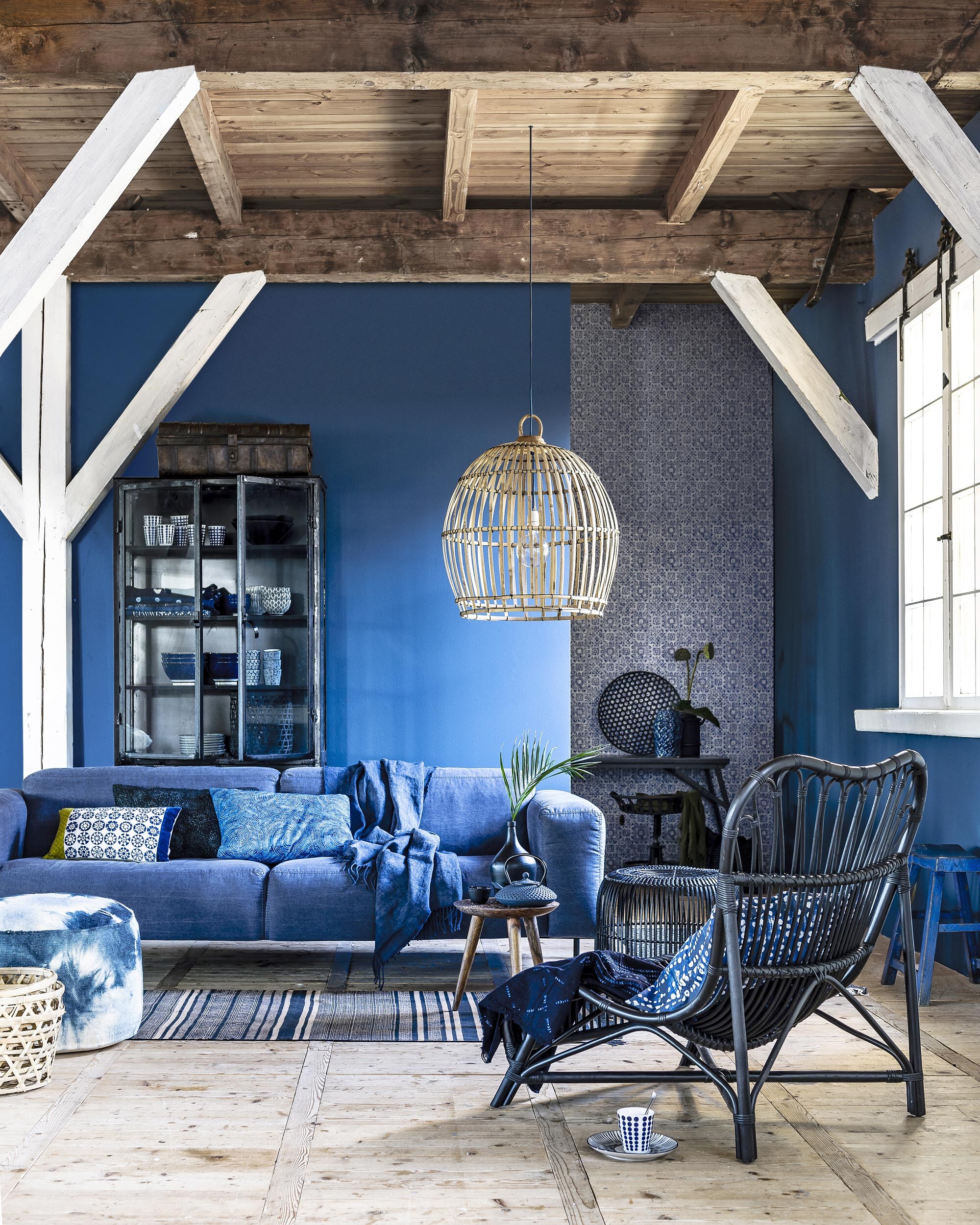 Oude zwarte apothekerskast, 200x90x40 cm (lxbxd) (). Erin: indigo koppen met stippen en strepen per 4 (). Indigo kommen, kopjes met indigo dessin Kyoto (). Kleine kommen met zwart-wit dessin Farro, schotel (). Diverse indigo tafelkleden, 150×220 cm (). Indigo doeken, 115×150 cm, tie-dye lap op de stoel (). Metalen koffer bovenop de kast, vierzitsbank van Diesel in stof jeans, 240 cm breed (). Kussen bekleed met zwart gebloemde batikstof Island Batik, kussen bekleed met blauw becirkelde batikstof Timeless Treasures (). Meerkleurig kussen (). Blauwe plaid Sienna Marine, 100% linnen, van Designers Guild 140×165 cm ). Zwarte bamboe kruk ().  Colone van House Doctor (vtwonen.nl). Kussen met tie-dye print (). Tie-dye poef ().  Rhombus blauw-grijs, 70×180 cm (vtwonen.nl).  Dutchbone by hand van Zuiver, met daarop  en kopje van Bredemeijer, zwart flesvaasje van HK Living (). Achterin:  van Bepure 50×174 cm,  van Bloomingville,  van Madam Stoltz,  van Nordal (). Zwarte bamboe schaal, zwarte bamboe mand in de kast (). Naturel bamboe manden vooraan (). Behang Serego-Cobalt van Designers Guild (). Hanglamp gemaakt van originele hanenmand (). Strijkijzersnoer Jeans (www.snoerboer.nl). Blauw krukje (). De wanden zijn geverfd met extra matte muurverf in de kleur Deep Steel ().
