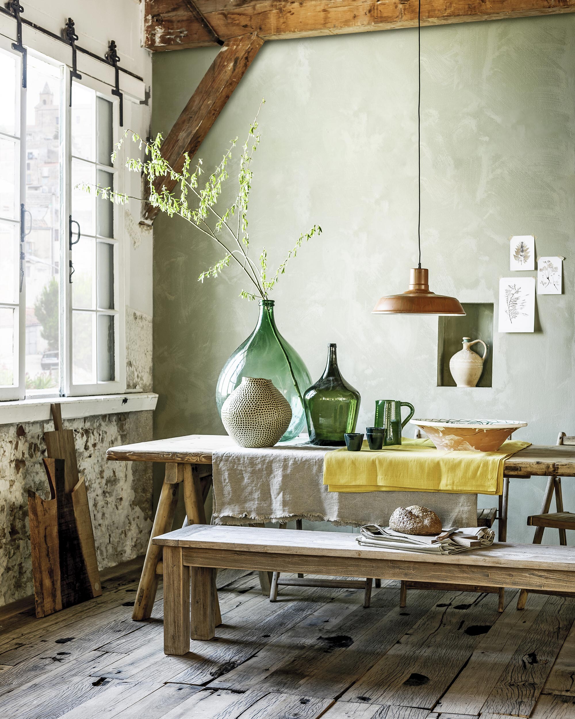, 260×90 cm, , 200x40x45 cm,  (Het Kabinet). Tegen de muur:  van Raumgestallt (vtwonen.nl). Ruwe broodplank twee tinten hout (). Op tafel: grote groene fles, kleinere fles, kruik in de nis (), vaas met stippen (). Groene karaf, donkergroene mokken, grote schaal (). Grof linnen 140 cm breed (). , elk 150×300 cm,  (Dille &amp; Kamille). Hanglamp Rusty (). De wand is geverfd met kalkverf in de kleur Artichaut (). Botanische illustraties privébezit.