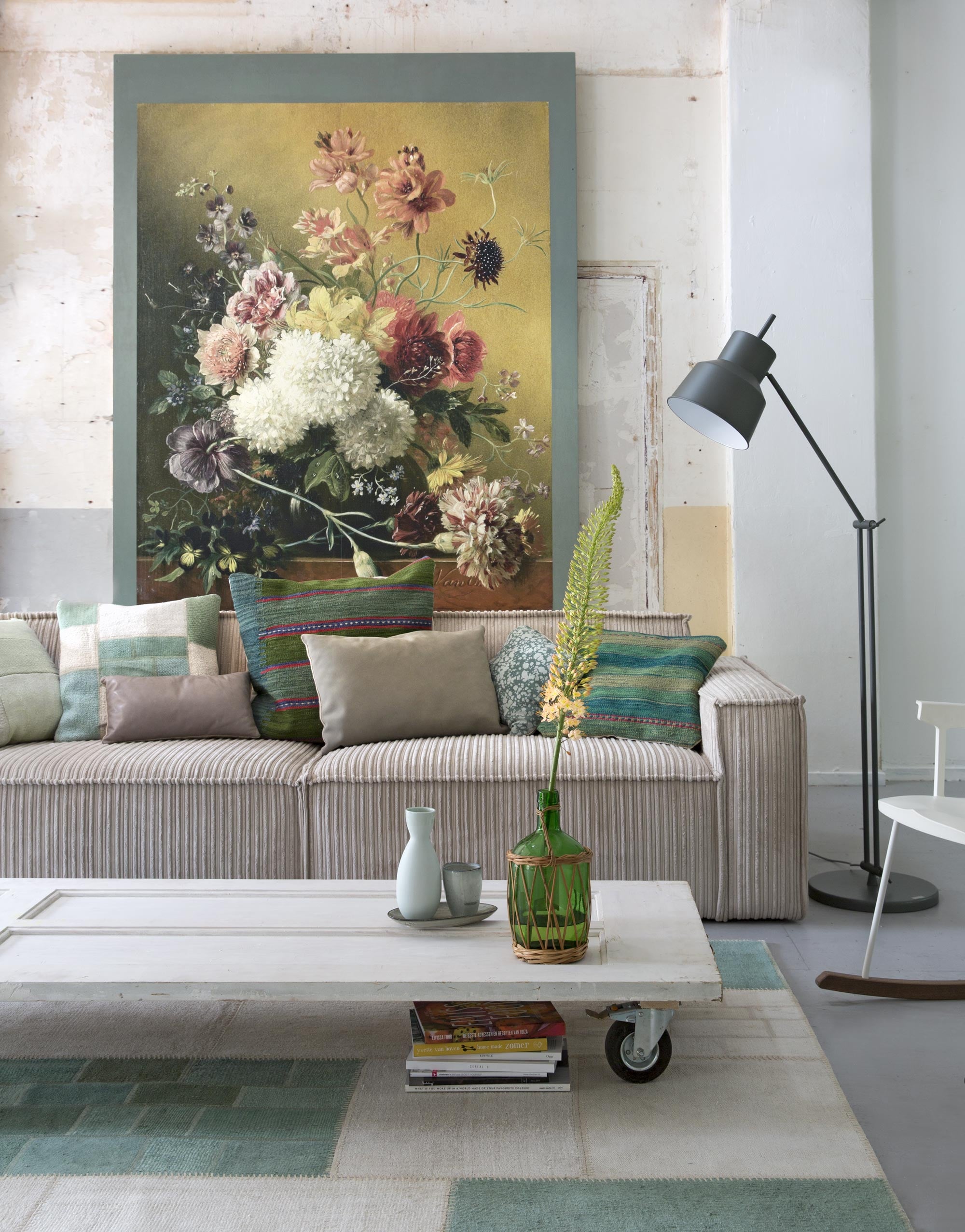Oude deur (). Print op de muur, groene verf naast print Outside van Aquamarijn ().  in beige ribstof (Basiclabel). Groen-beige geblokt , kelim kussens groen gestreept Persisk,  groen-beige geblokt Mejrup (Ikea). Kelim kussen lichtgroen geblokt (). Kussens groen leer van Sprdlx groot en klein ().  van Marika Giacinti (Friday Next).  Comeback van Kartell (Anno Design). Vloerlamp van It’s about Romi (). Schaaltje en beker van Broste (). Flesvaas (kringloopwinkel).